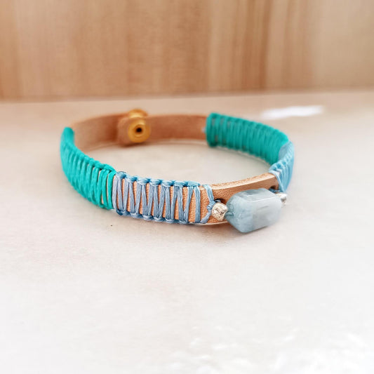 Ocean's Embrace Aquamarine & Crazy Horse leather bracelet. Handcrafted pale blue & seafoam green macrame, gold snap closure on flat surface.
