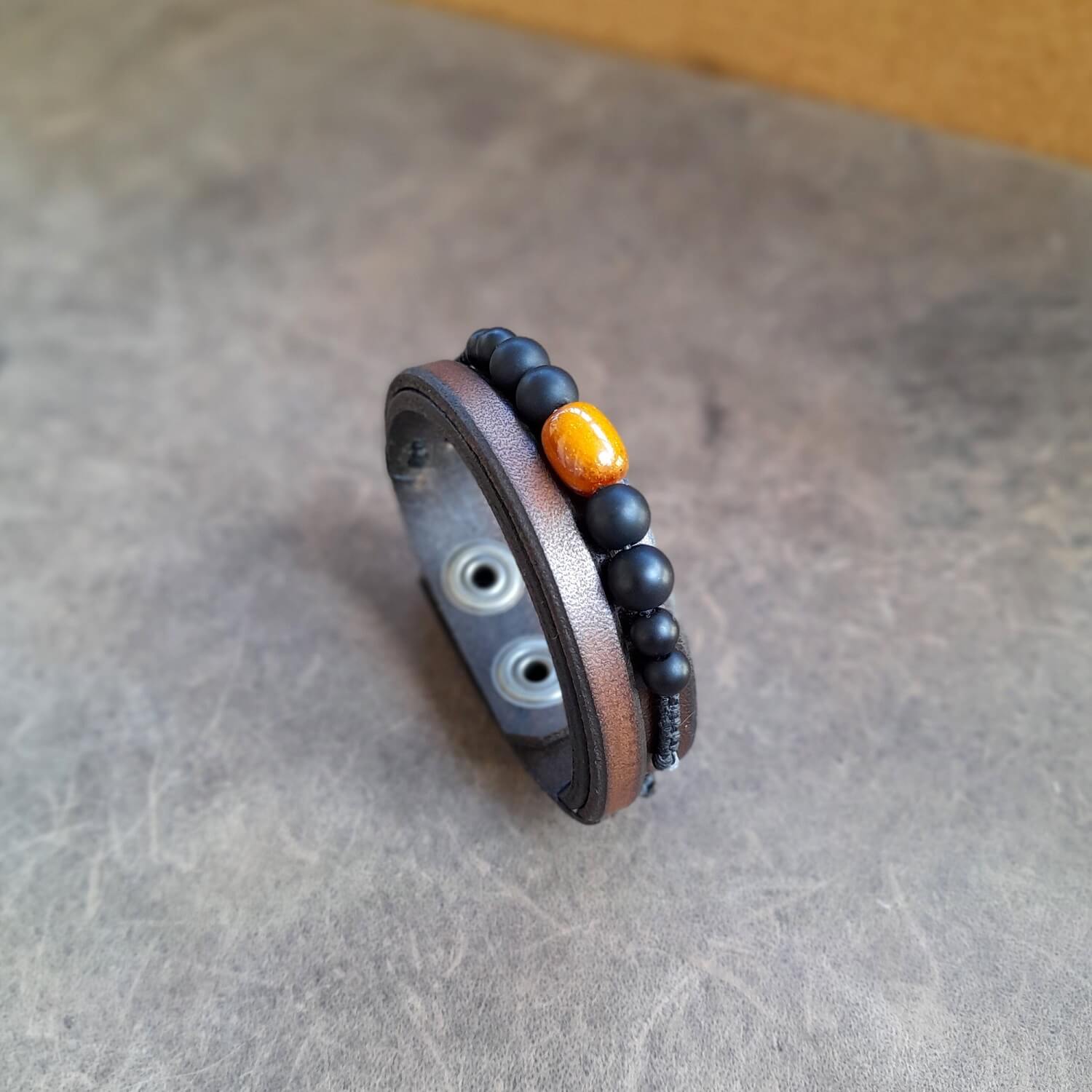 Side view of the leather beaded bracelet, showing thickness and bead details of matte black onyx and amber barrel.
