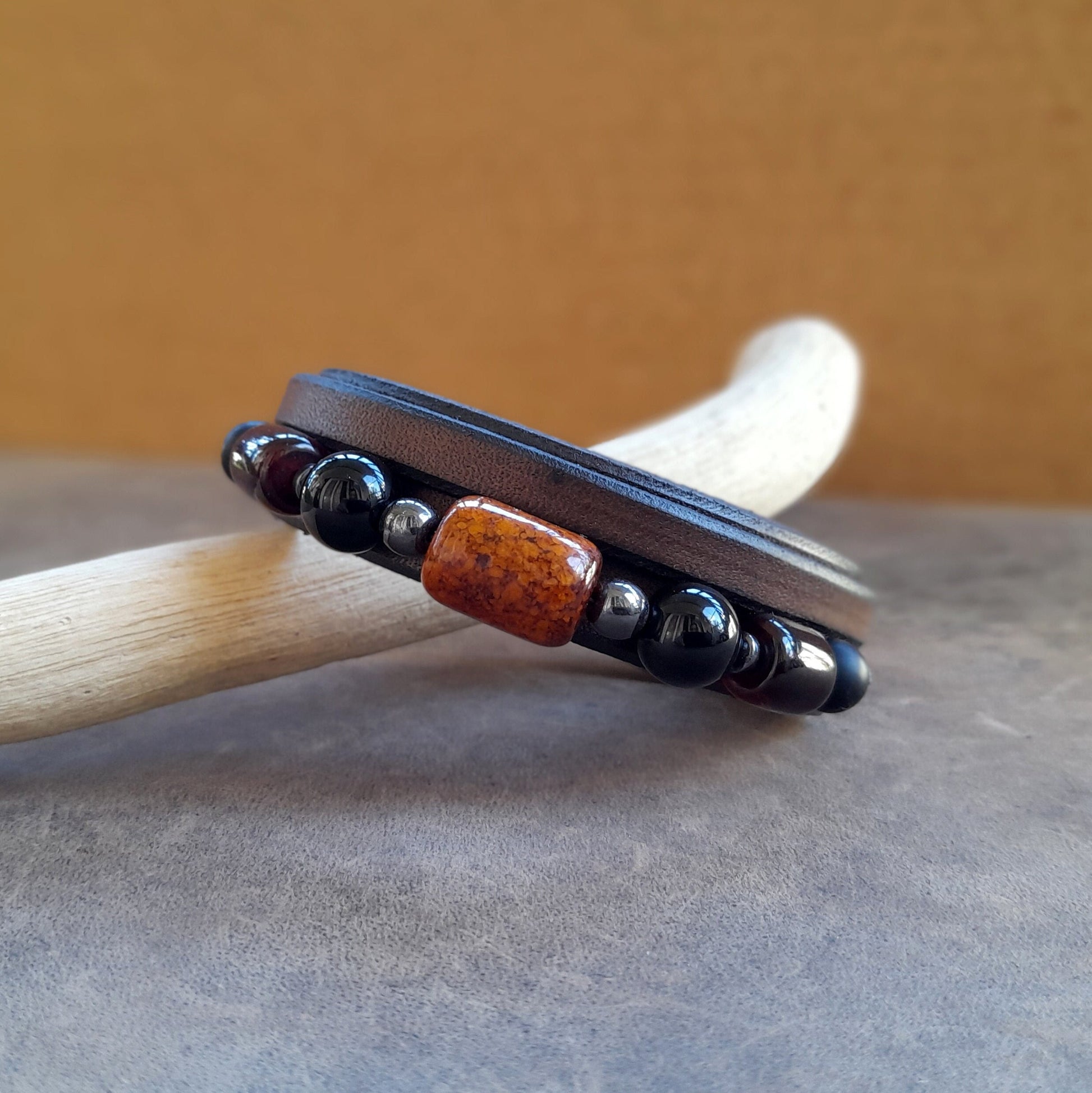 Other Detailed close-up of The Earth & Sky Harmony Bracelet, focusing on the polished Black Onyx beads and the warm, translucent Amber barrel bead against the chestnut leather.