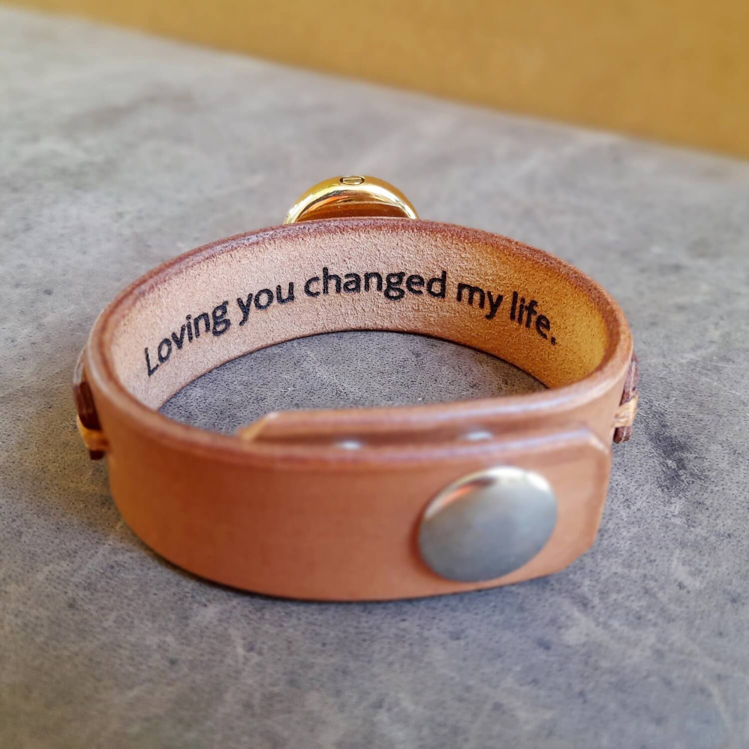 The Brown variation of the Personalized Cremation Urn Leather Cuff underside view with custom secret message that reads "Loving you changed my life"