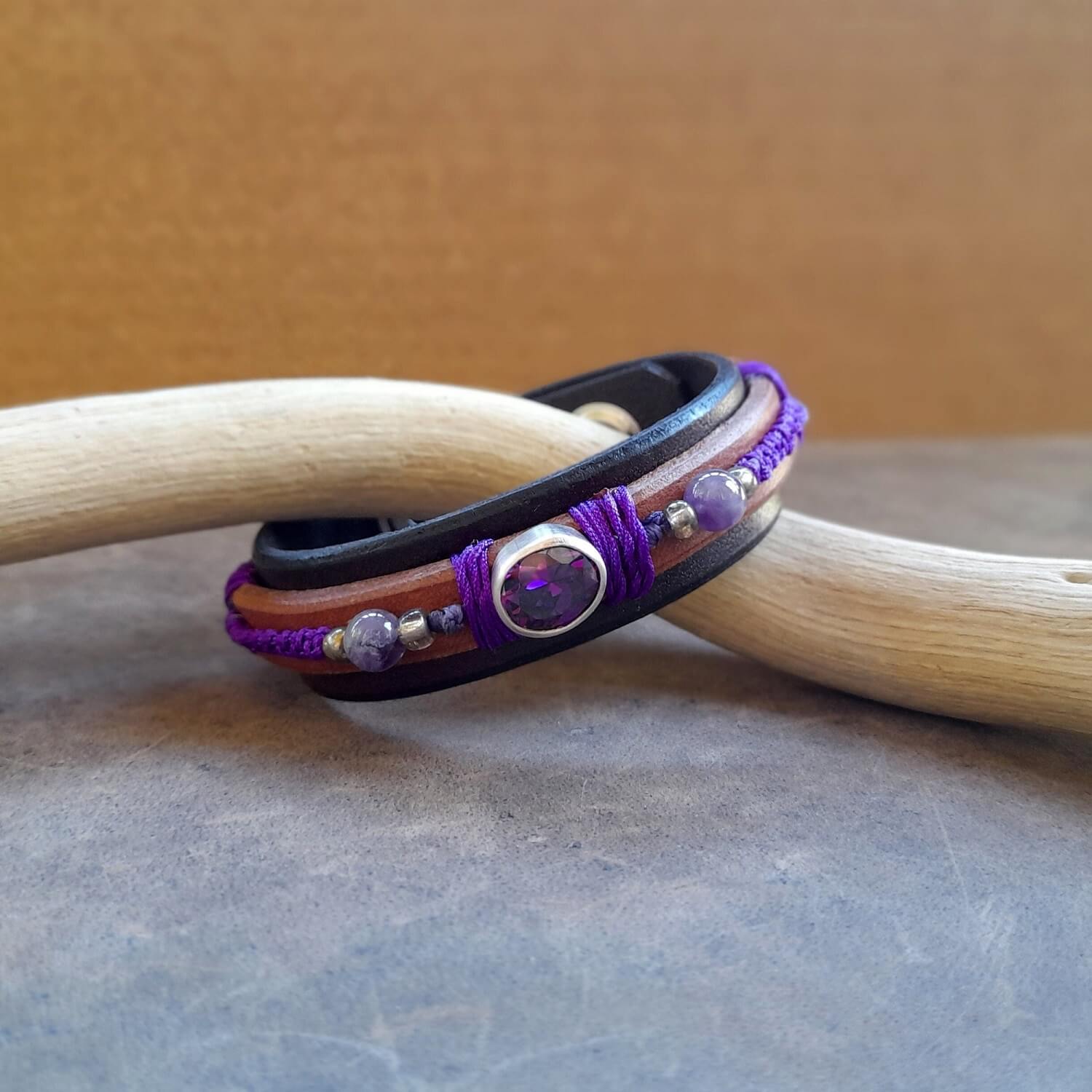 The OOAK Purple Zirconia Bracelet: A layered dark brown and brown leather bracelet featuring a sparkling purple cubic zirconia on a sterling silver pendant, with deep purple macramé and natural amethyst beads.