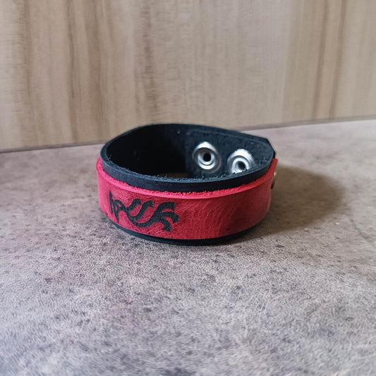 Adjustable leather bracelet with a black base band and a red top layer featuring a Vermilion Bird silhouette, with two rivets and a stainless steel snap button closure.