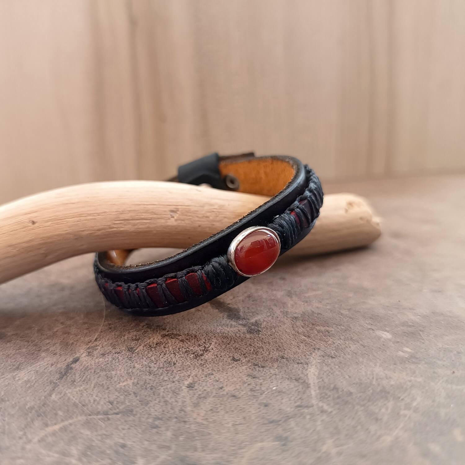 Detailed close-up side view main picture of the handcrafted sterling silver pendant set with the vibrant red Carnelian gemstone on The Roamer leather Bracelet, highlighting its intricate setting and color.