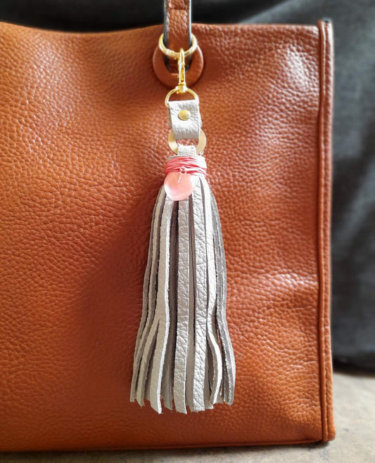 OOAK Rose Quartz Heart Charm with a gray leather tassel, clipped on a bag. Features a genuine Rose Quartz heart pendant wrapped with bright pink thread. Comes with a brass gold-tone O-ring and lobster clasp.