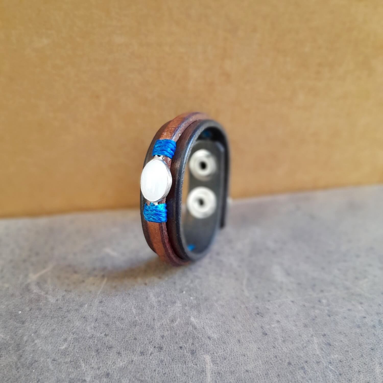 Side view of the leather bracelet with opal pendant, showing two layers of leather and silver snap buttons.