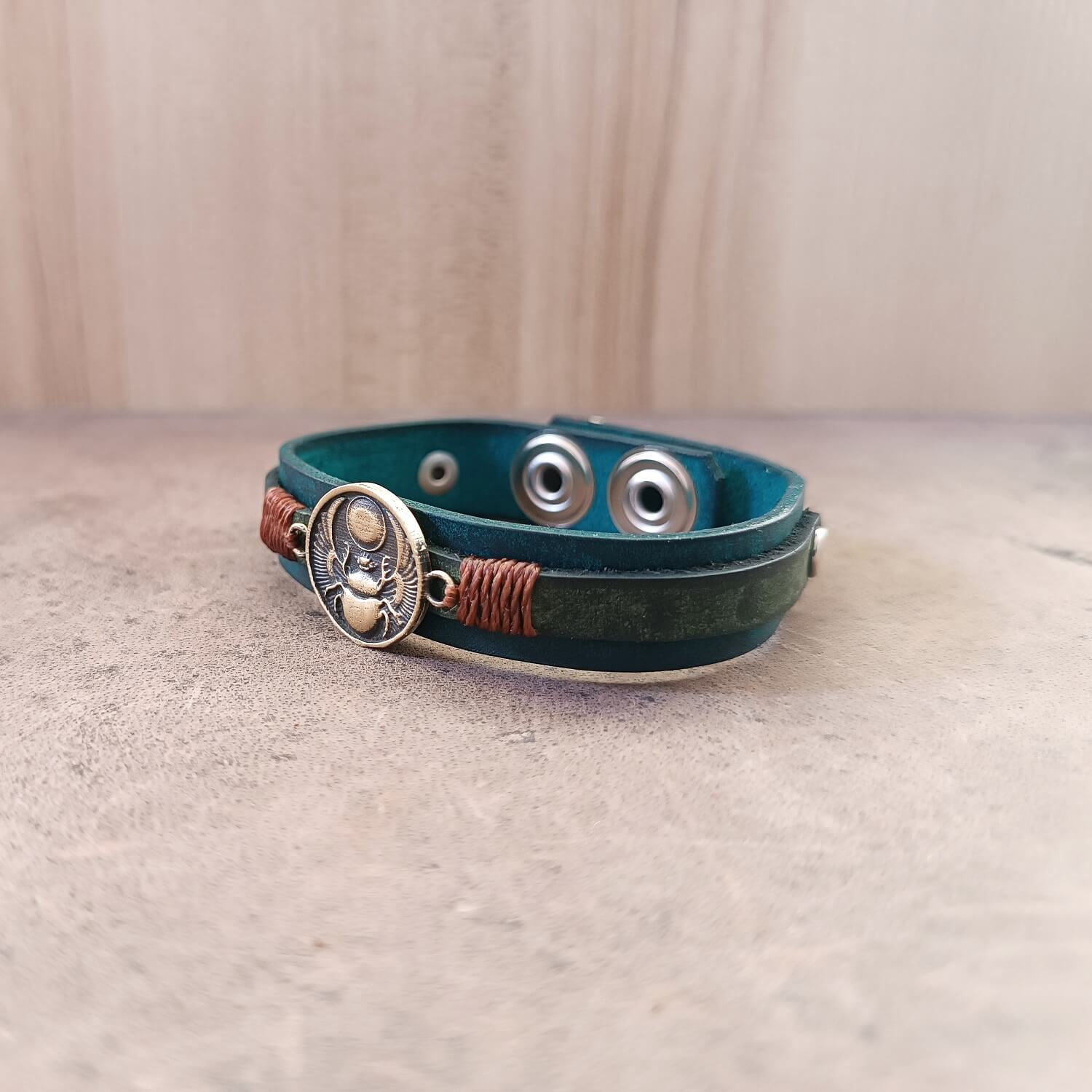Side view of Solar Scarab Bracelet, showing the layered dark petrol blue Crazy Horse leather with hand-dyed black bubble technique and the scarab charm.