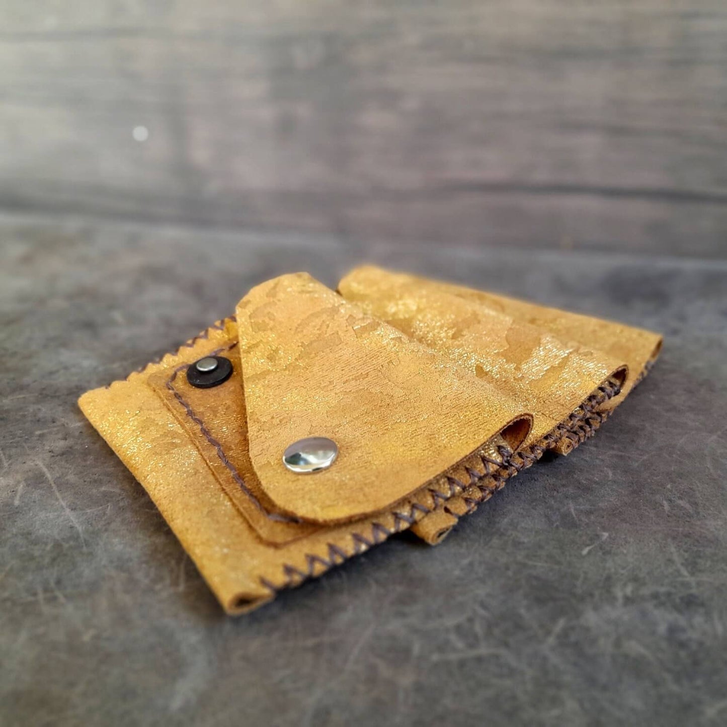 Side profile of the Gold leather mini wallets, revealing its snap closure and slim profile when closed.