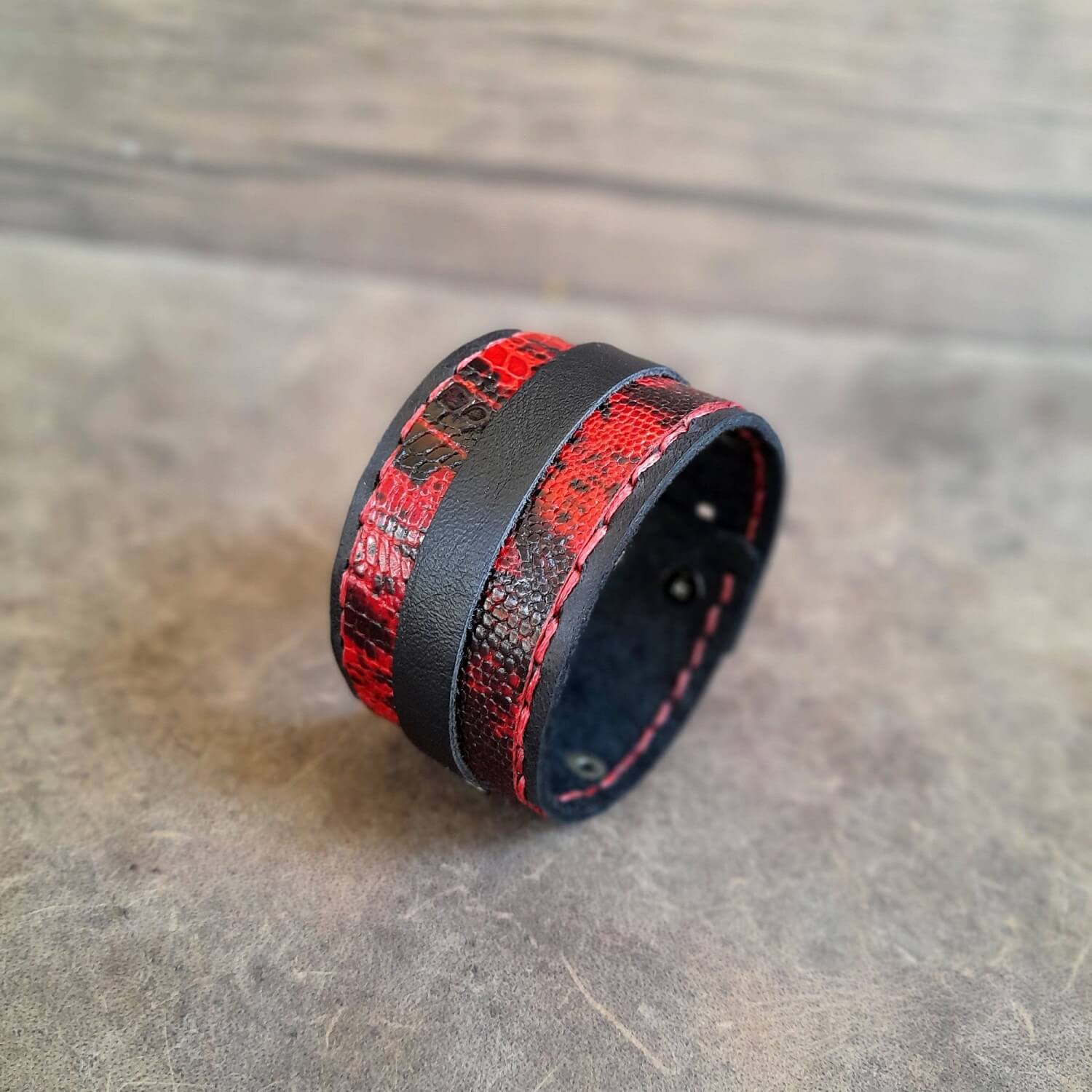 Red and black leather cuff bracelet on a wooden surface