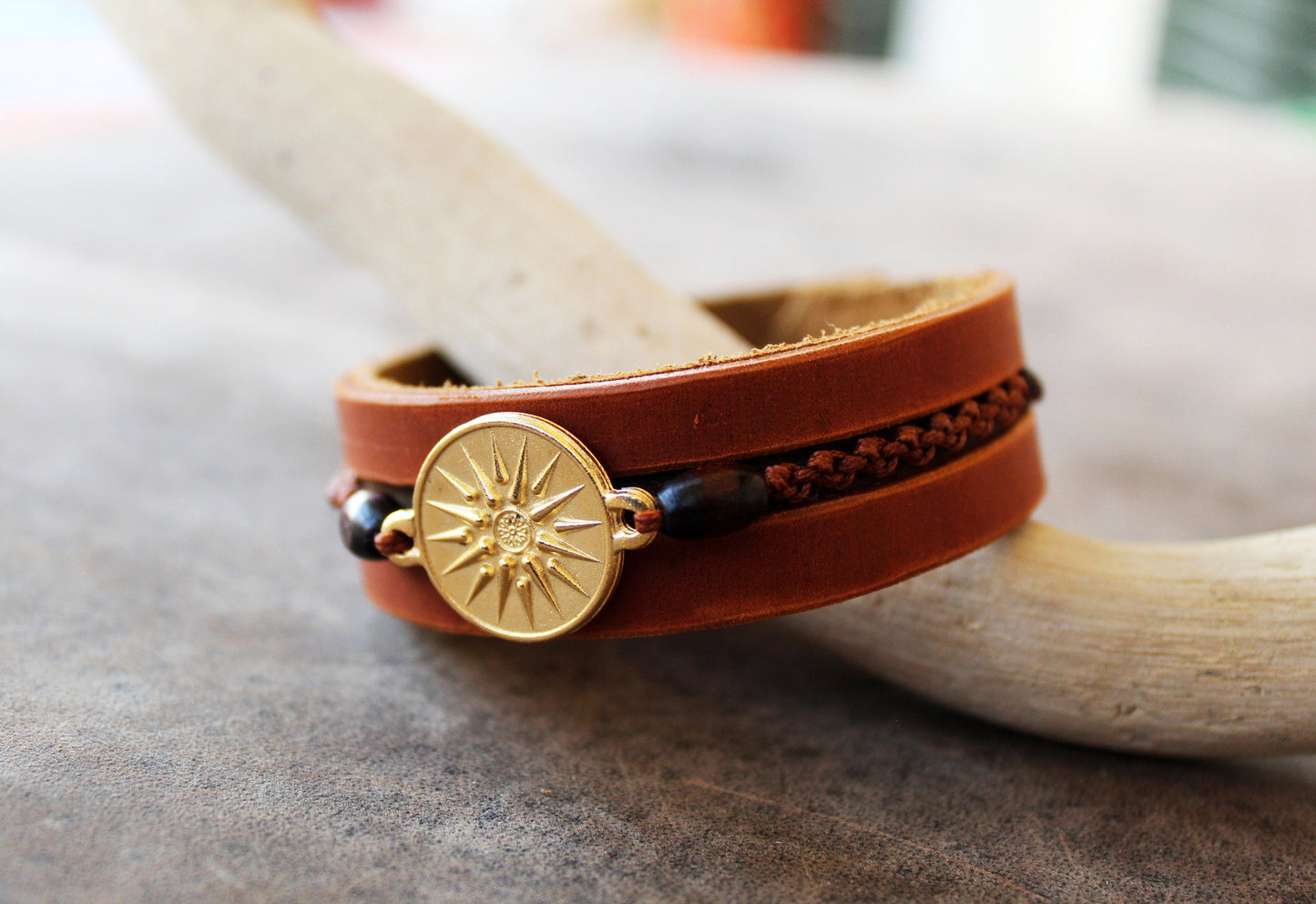 Side view of Gold Vergina Sun Leather Bracelet, showing three layers of brown leather, hand-stitching, wooden beads, and macrame.