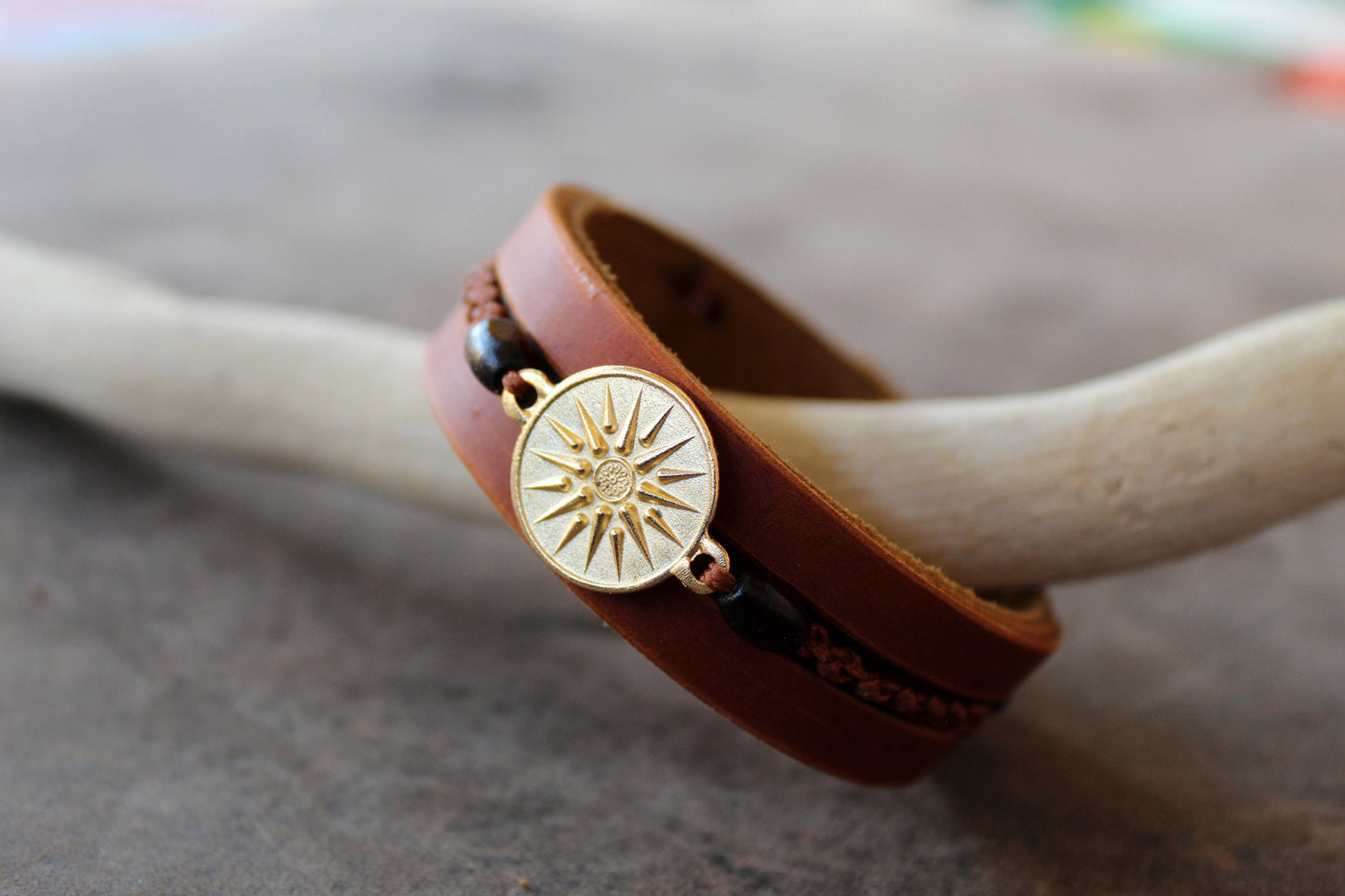 Side view of Gold Vergina Sun Leather Bracelet, showing three layers of brown leather, hand-stitching, wooden beads, and macrame.