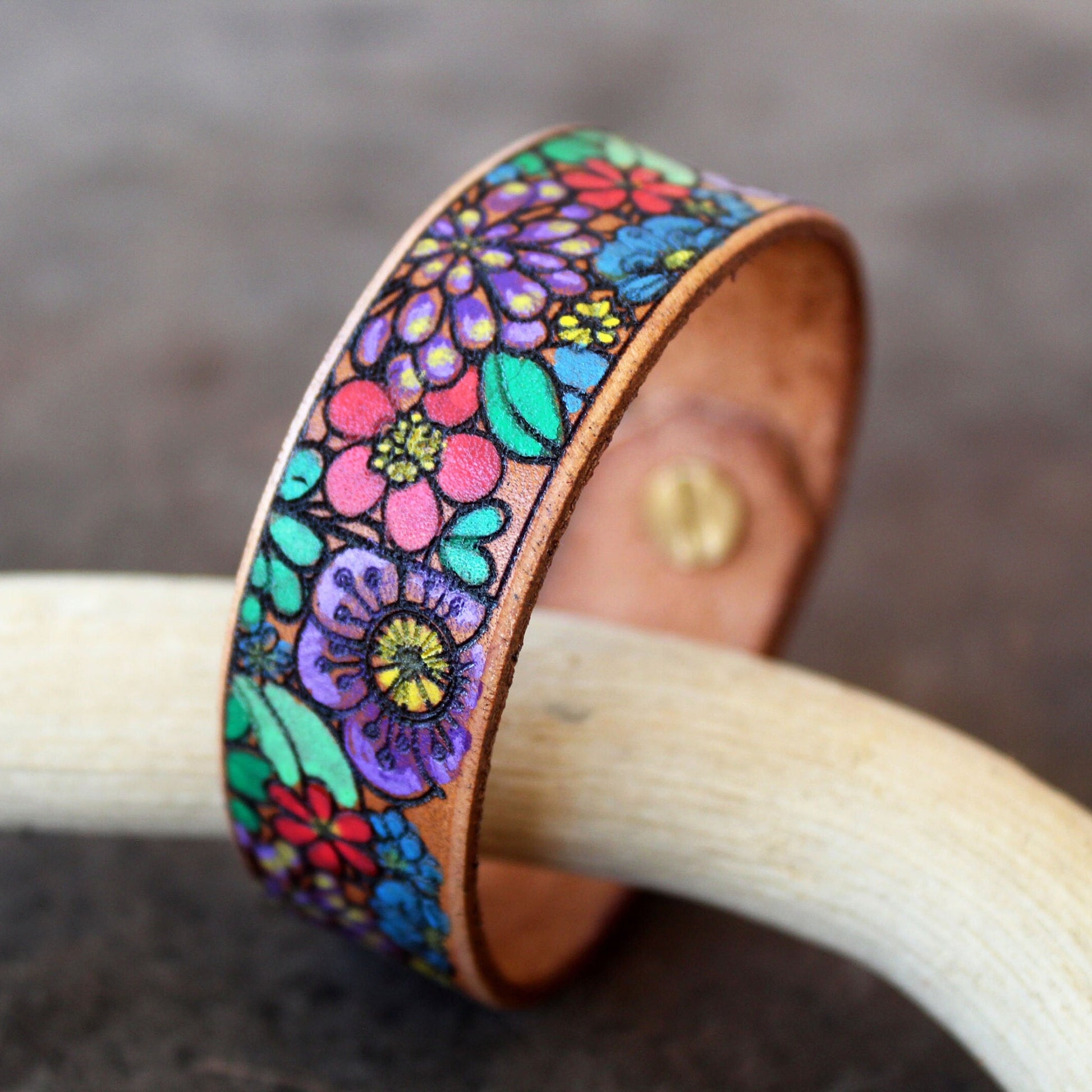 Side view of Hand-Painted Flowers Bracelet, showing its 2cm width and hand-painted design wrapping around the leather band, revealing its depth.