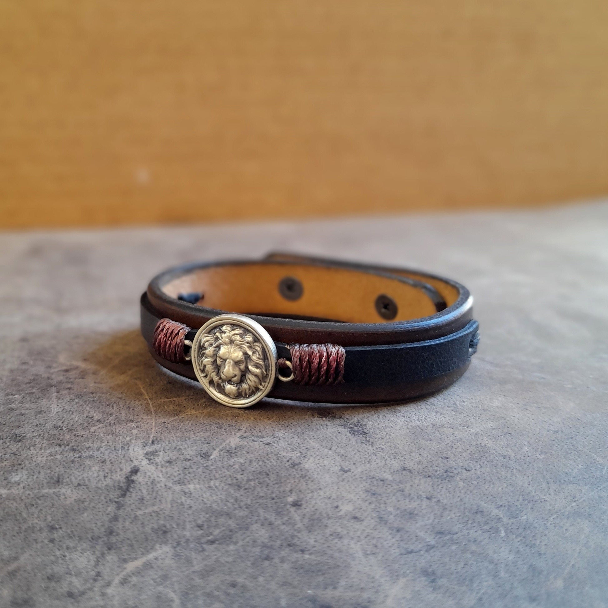 Side view of Lion Leather Bracelet, showing layers of chestnut brown and black full-grain leather and snap button closure.