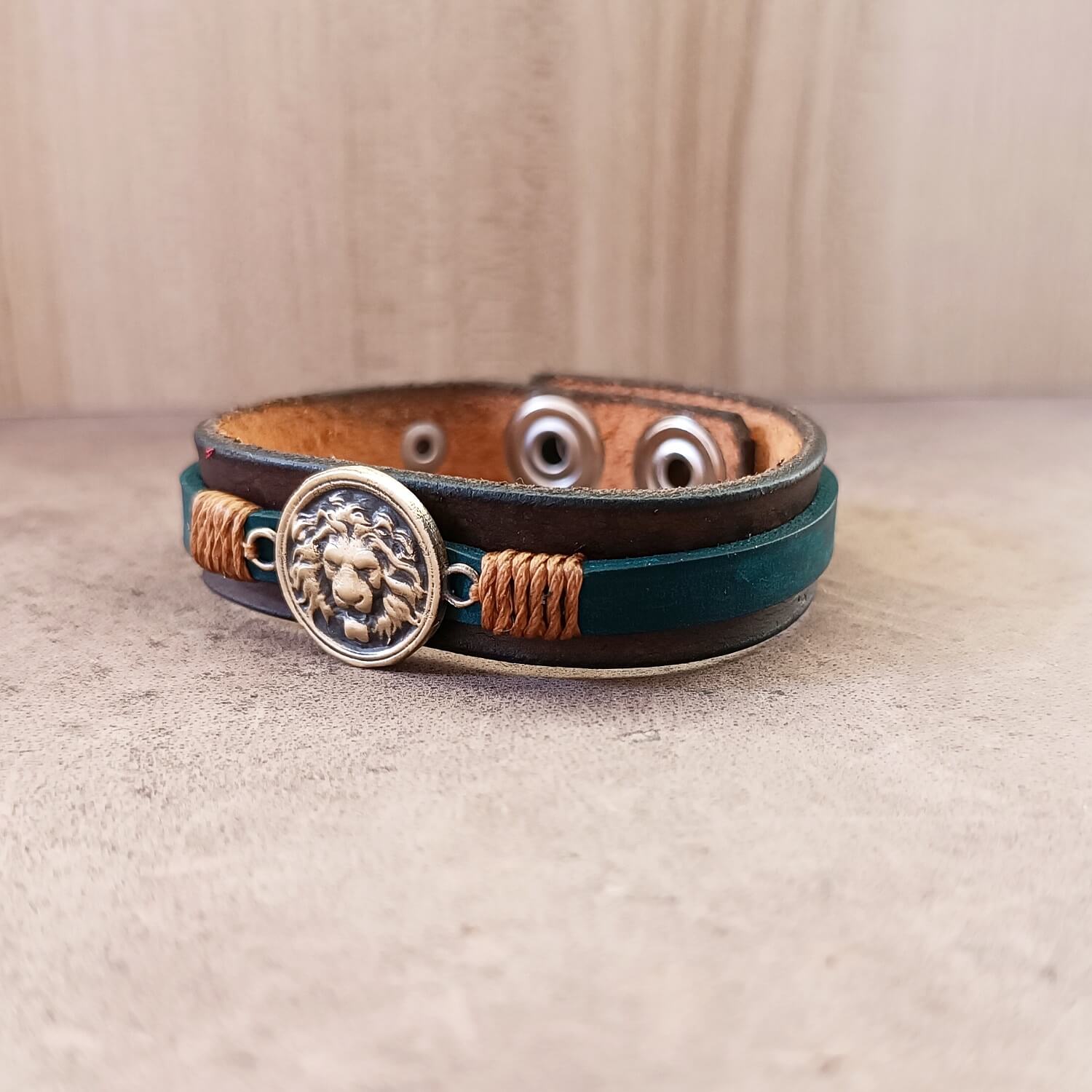 Leather bracelet with lion emblem on a beige surface