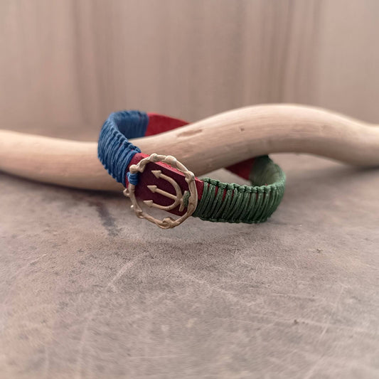 Side view of The Guardian's Balance Trident Bracelet, showing the thickness of the vibrant red Crazy Horse leather band and the intricate deep forest green and navy blue macrame knotting.