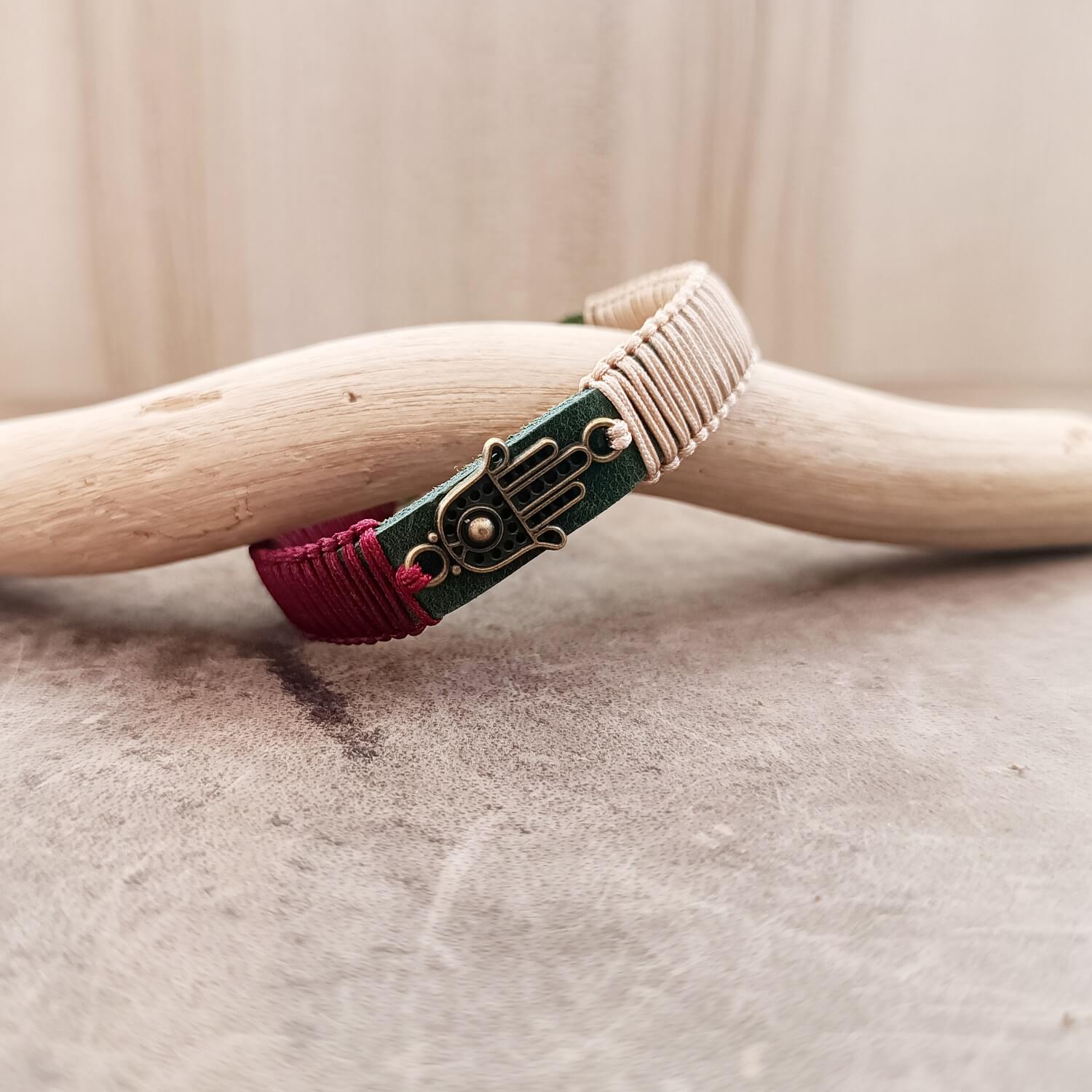 Close-up of The Hamsa Harmony Bracelet, highlighting the intricate details of the antique bronze Hamsa Hand pendant and the texture of the macrame cords against the khaki leather.