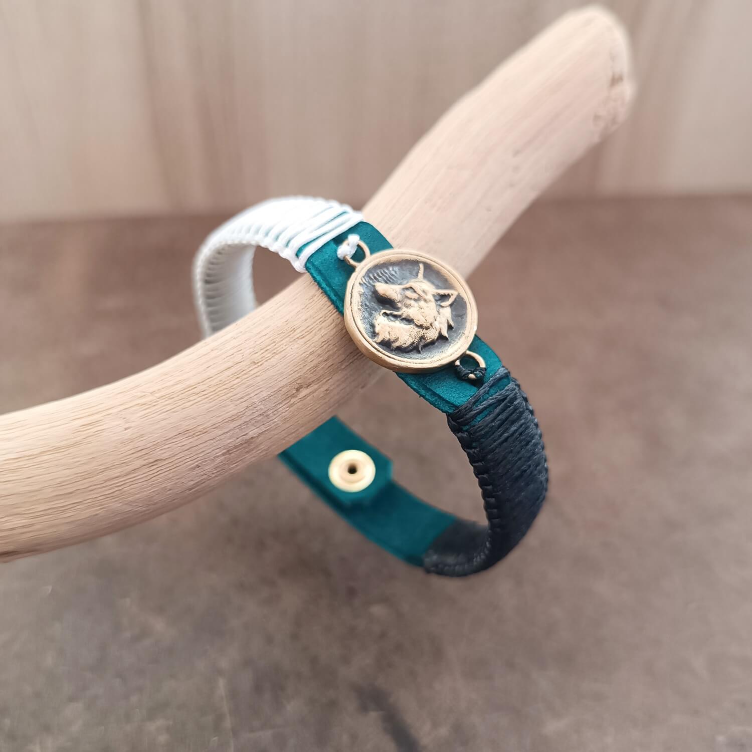 Side view of The Instinctive Shield Wolf Bracelet, showing the thickness of the blue Crazy Horse leather band and the intricate white and black macrame knotting.