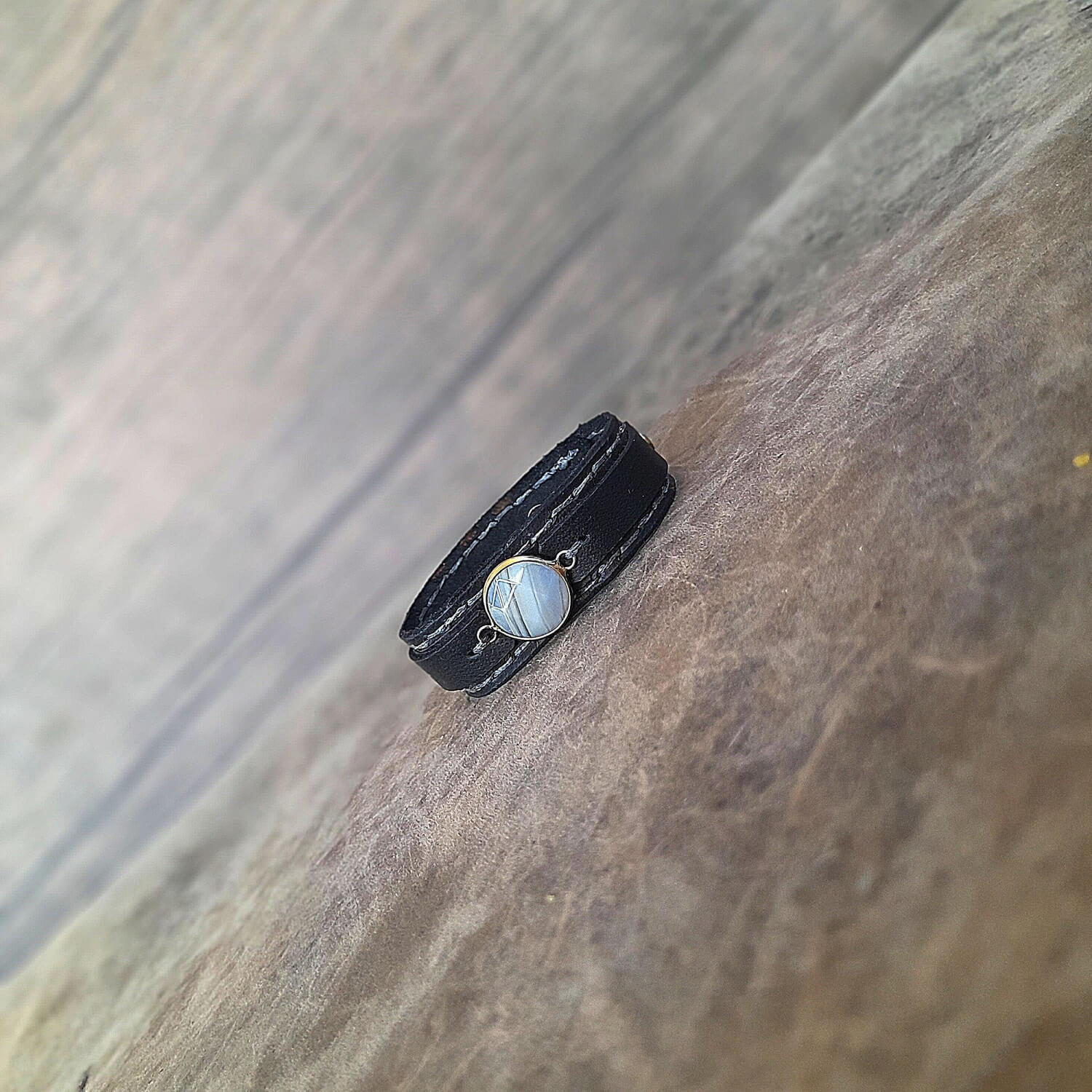 The Obsidian Cuff: An OOAK men's black leather bracelet featuring a gold-plated agate cabochon with light and dark gray veins, and deep gray hand-stitched details.