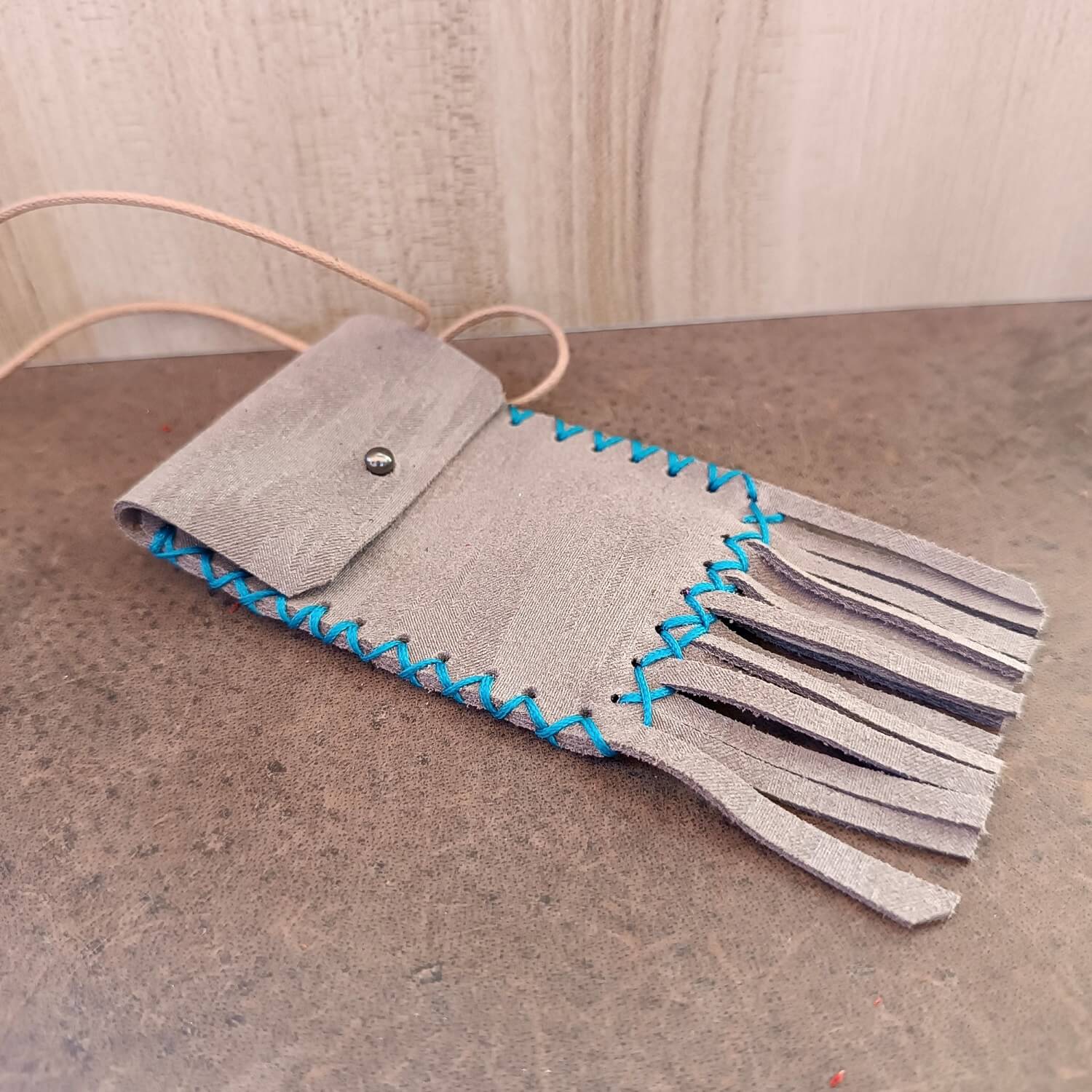 Side profile of the Shimmering Gray Leather Neck Bag, illustrating its slim profile and the depth of the pouch.