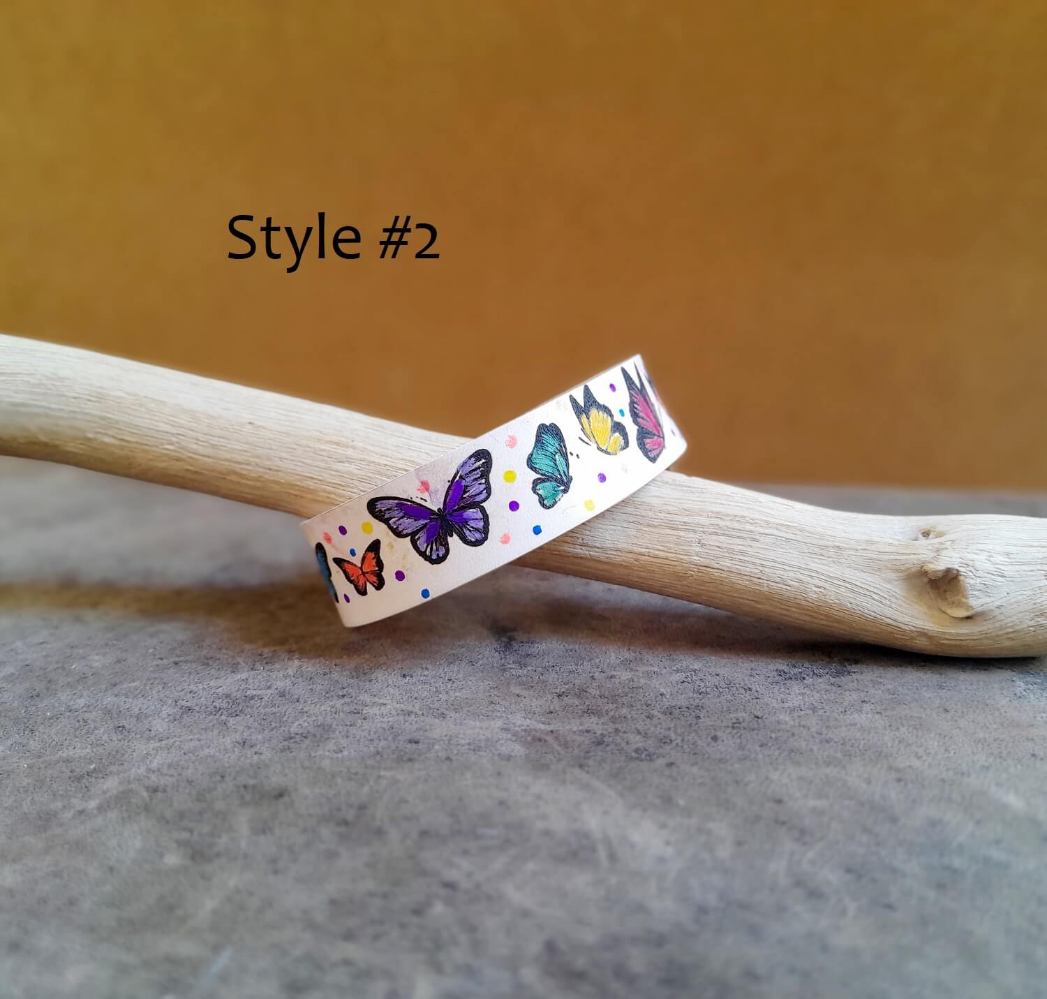 Colorful butterfly-themed band on a wooden stick with a brown background - Style #2