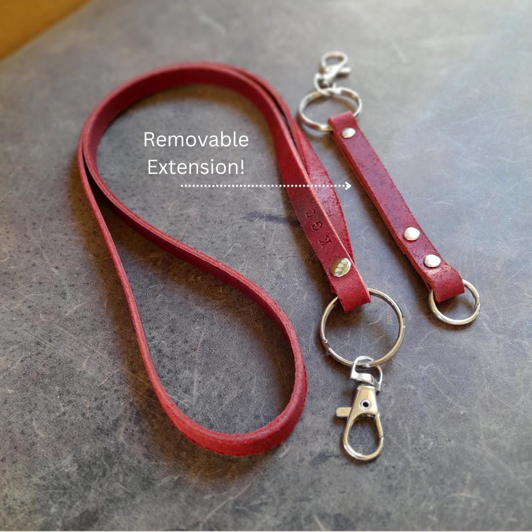 The Adapt Lanyard in Burgundy Red, shown at its shorter length without the extension, with the extension laid flat next to it. Highlights the personalized leather, large 3cm split rings, and main stainless steel lobster clasps.