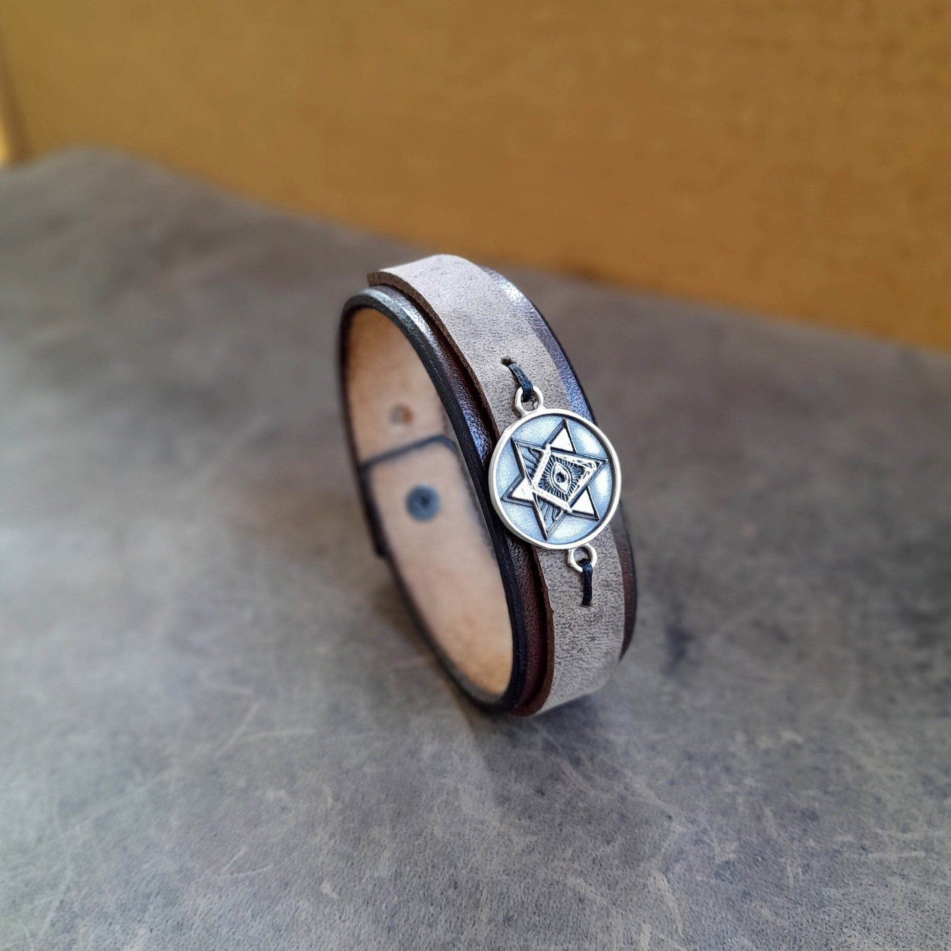 The All Seeing Eye Leather Bracelet: A layered chestnut brown and charcoal full-grain leather cuff featuring a prominent Sterling Silver 925 Eye of Providence pendant.