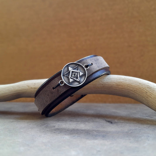 The All Seeing Eye Leather Bracelet front view: A layered chestnut brown and charcoal full-grain leather cuff featuring a prominent Sterling Silver 925 Eye of Providence pendant.