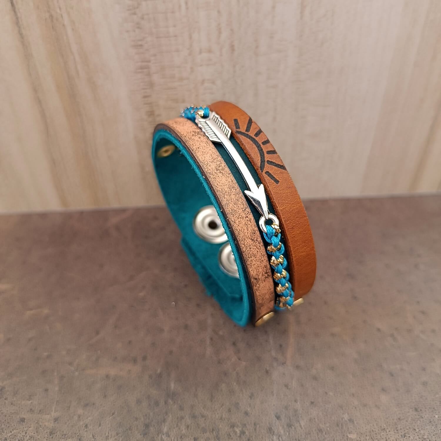 A layered multistrand leather bracelet inspired by the Scout’s prestigious Arrow of Light award, featuring a silver arrow and engraved 7 rays sun.