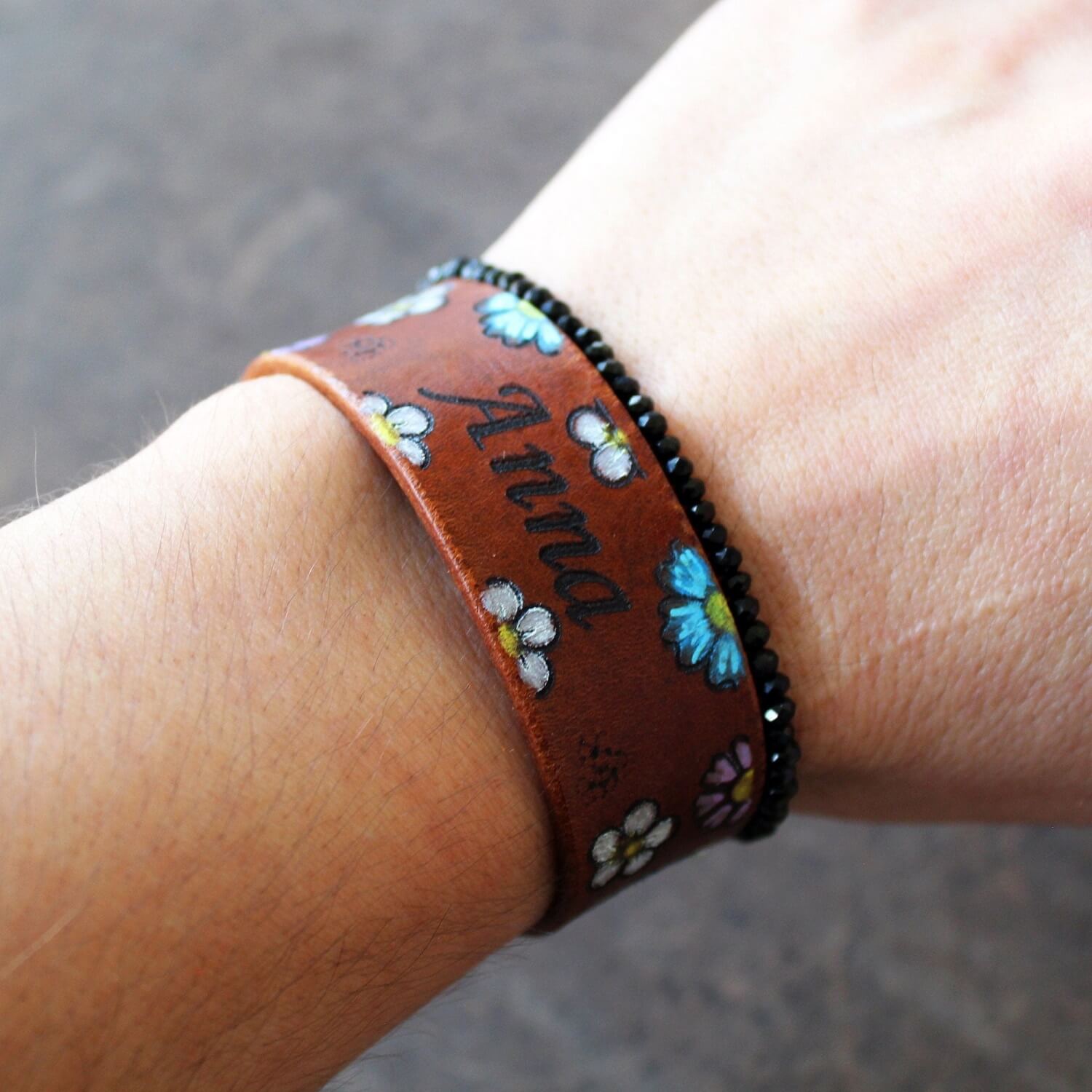The Bloom & Name Bracelet worn on a wrist, showcasing its 2 cm wide profile, hand-painted floral design, and personalized name, fitting elegantly for everyday wear.
