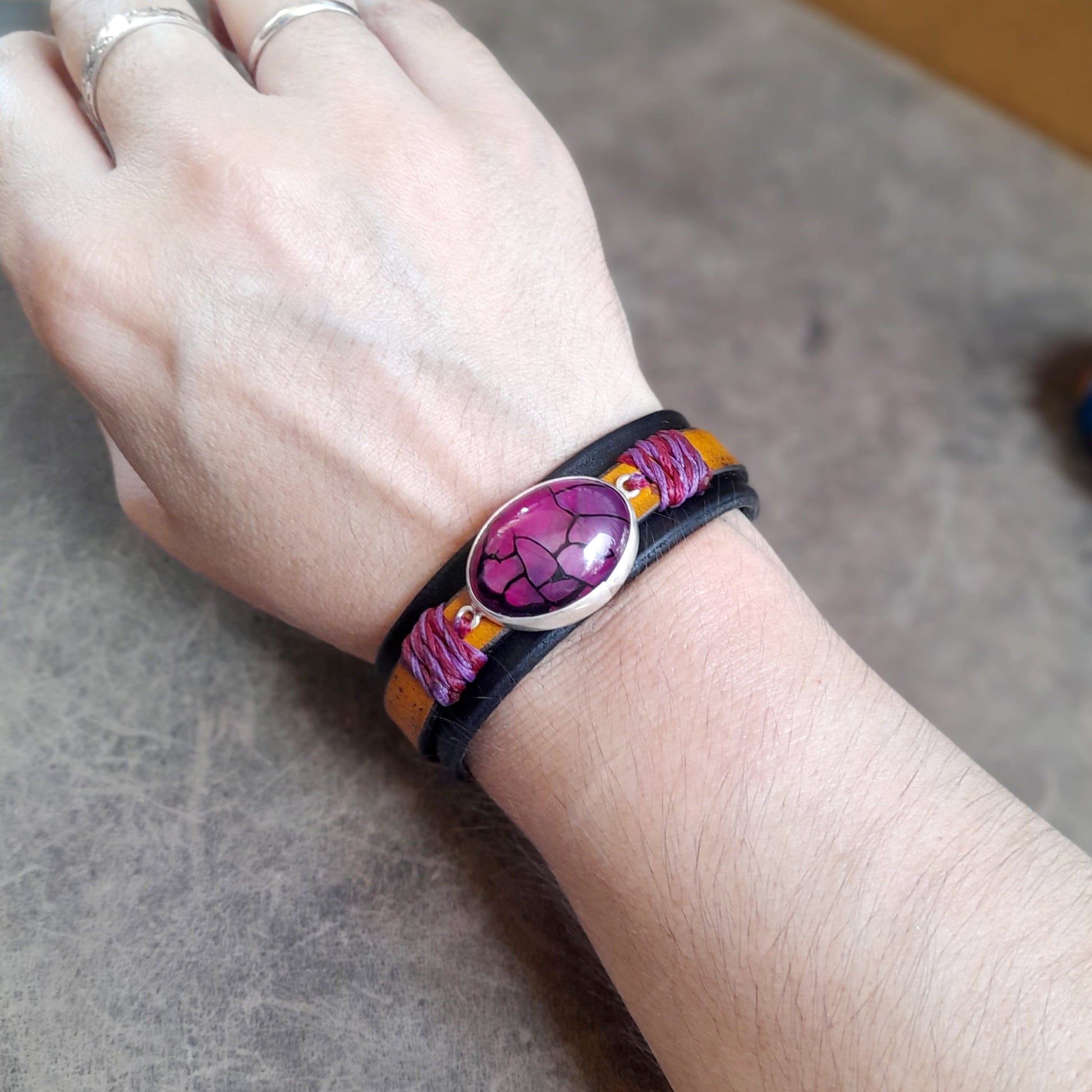 The Dragon Heart Bracelet worn on a wrist, demonstrating its comfortable fit, the bold presence of the stone, and the "savage style" of the leather cuff.