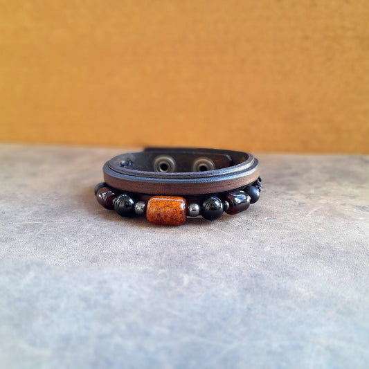 The Earth & Sky Harmony Bracelet, an OOAK men's piece. Features a chestnut brown Crazy Horse leather band adorned with a row of natural Black Onyx beads and a prominent Amber barrel bead.