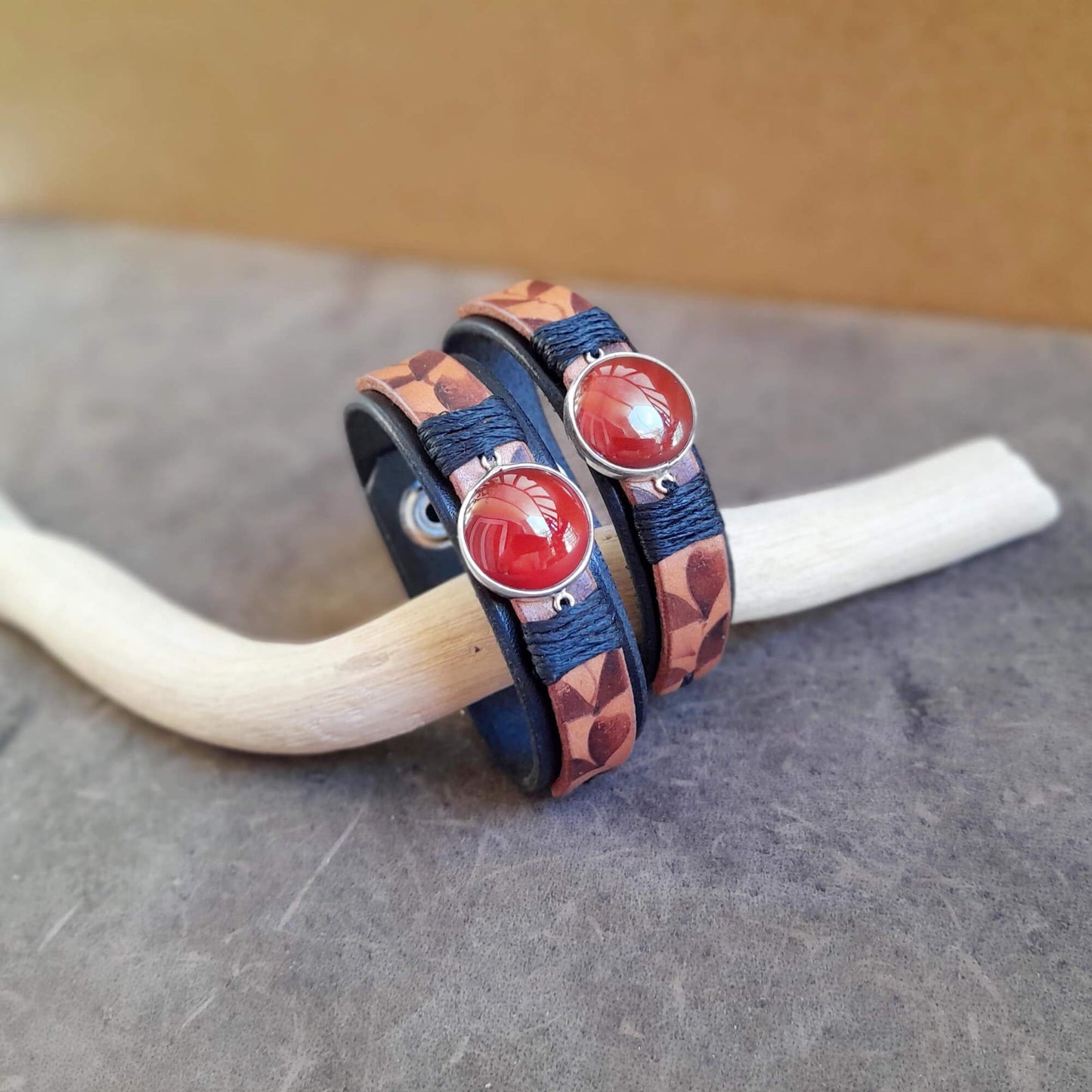 Two Ember Bloom Cuffs displayed side-by-side, showcasing them as a matching pair. Both bracelets feature hand-pyrographed leather and Red Carnelian in sterling silver pendants.