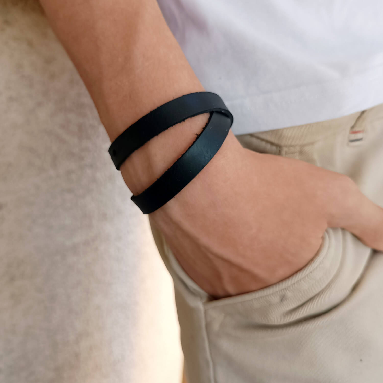 The Evolve Choker/Bracelet worn as a minimalist double-wrap bracelet on a man's wrist, showcasing its sleek black Crazy Horse leather.
