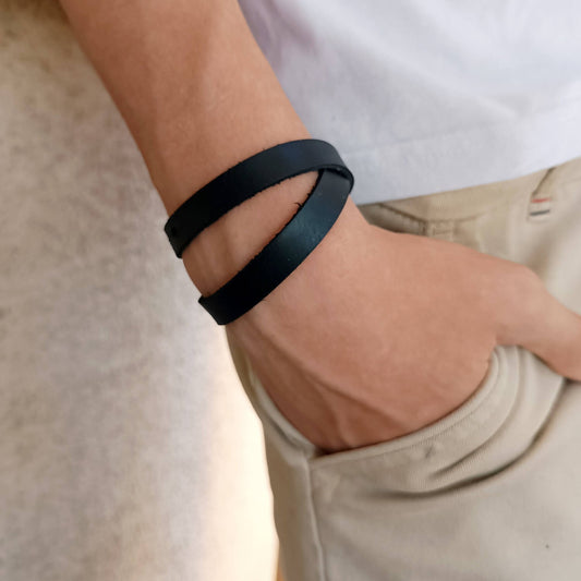 The Evolve Choker/Bracelet worn as a minimalist double-wrap bracelet on a man's wrist, showcasing its sleek black Crazy Horse leather.