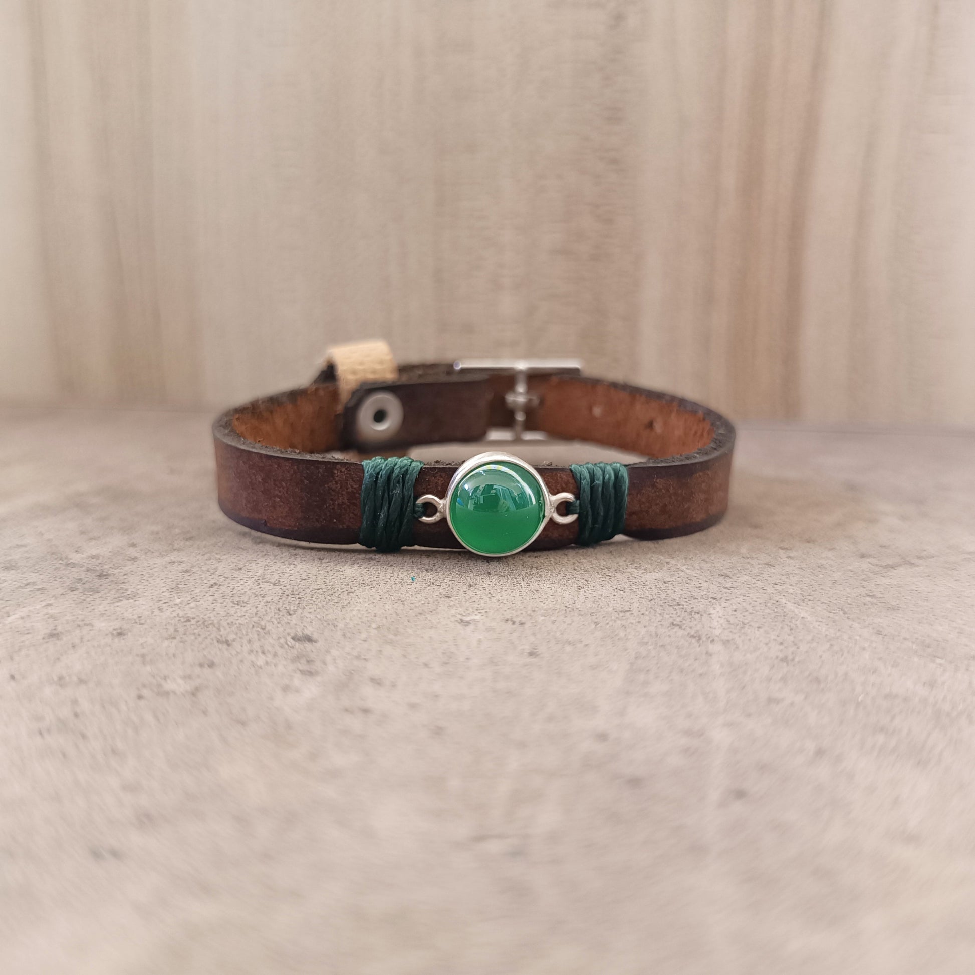 The Forest Whisper Bracelet, a one-of-a-kind minimalist leather wrap bracelet. Shows the rustic brown leather band with a sterling silver pendant holding a green aventurine gemstone.