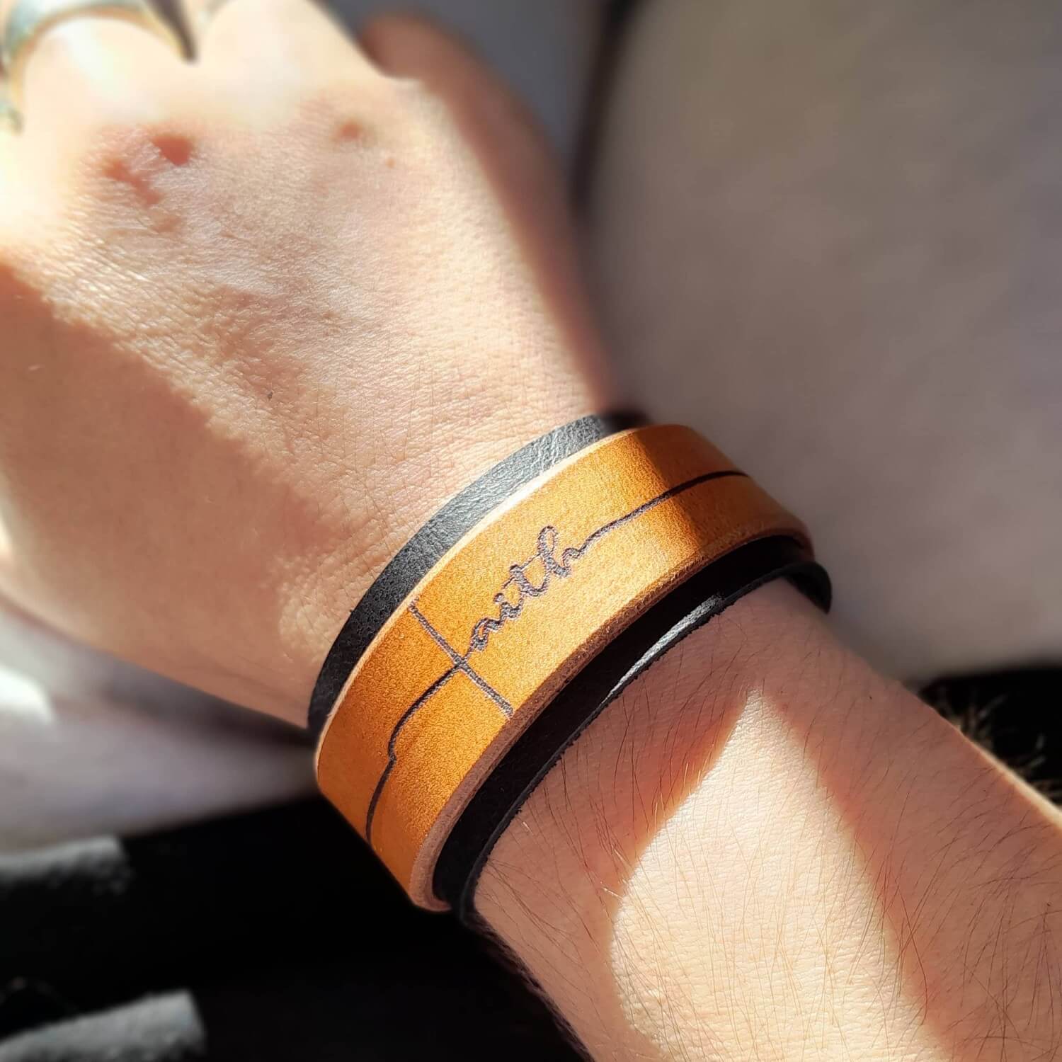 The Freedom Leather Cuff Bracelet worn on a wrist, showcasing its 3 cm wide design, black and brown leather, and powerful statement.