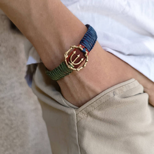 The Guardian's Balance Trident Bracelet worn on a wrist, showcasing its vibrant design, striking red leather, and symbolic brass trident pendant. Handmade by Lucky Seven Leather's Soulful Echoes Collection.