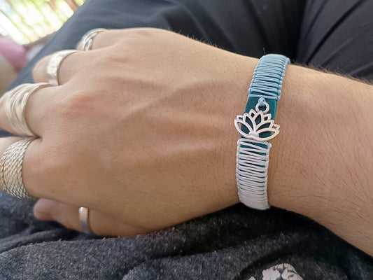 The Lotus's Serenity Bracelet worn on a wrist, showcasing its elegant design, tranquil blue leather, and symbolic lotus flower pendant. Handmade by Lucky Seven Leather's Soulful Echoes Collection.
