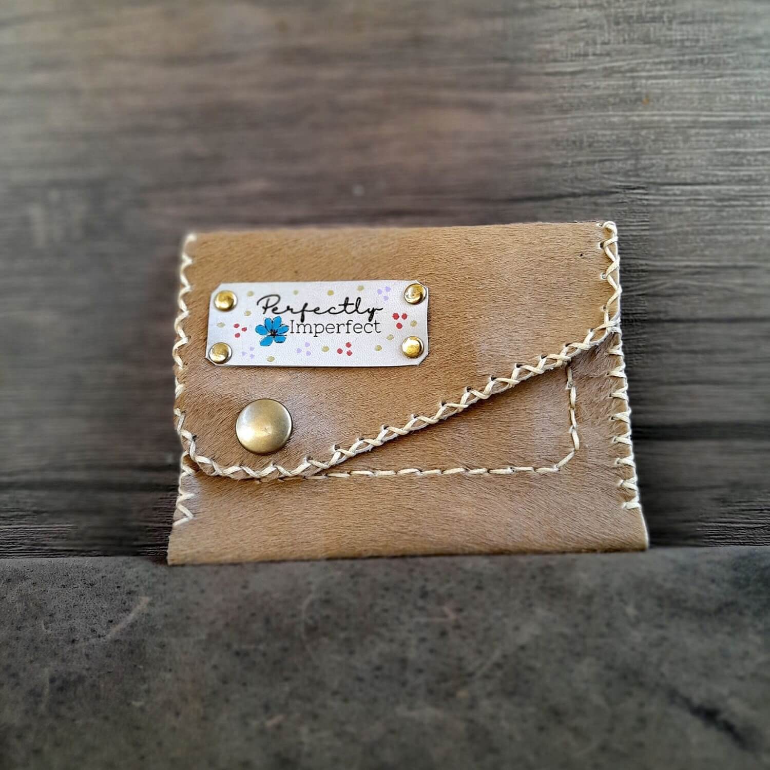 The OOAK Hair on Hide Women's Wallet: A unique light brown/beige pony skin leather wallet with an oval shape, a secure snap closure, and a visible "Perfectly Imperfect" leather tag.