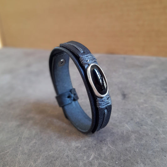 The OOAK Minimalist Black Obsidian Leather Bracelet: A sleek, layered black full-grain leather bracelet featuring an oval natural black obsidian stone on a sterling silver pendant, wrapped with black cord.