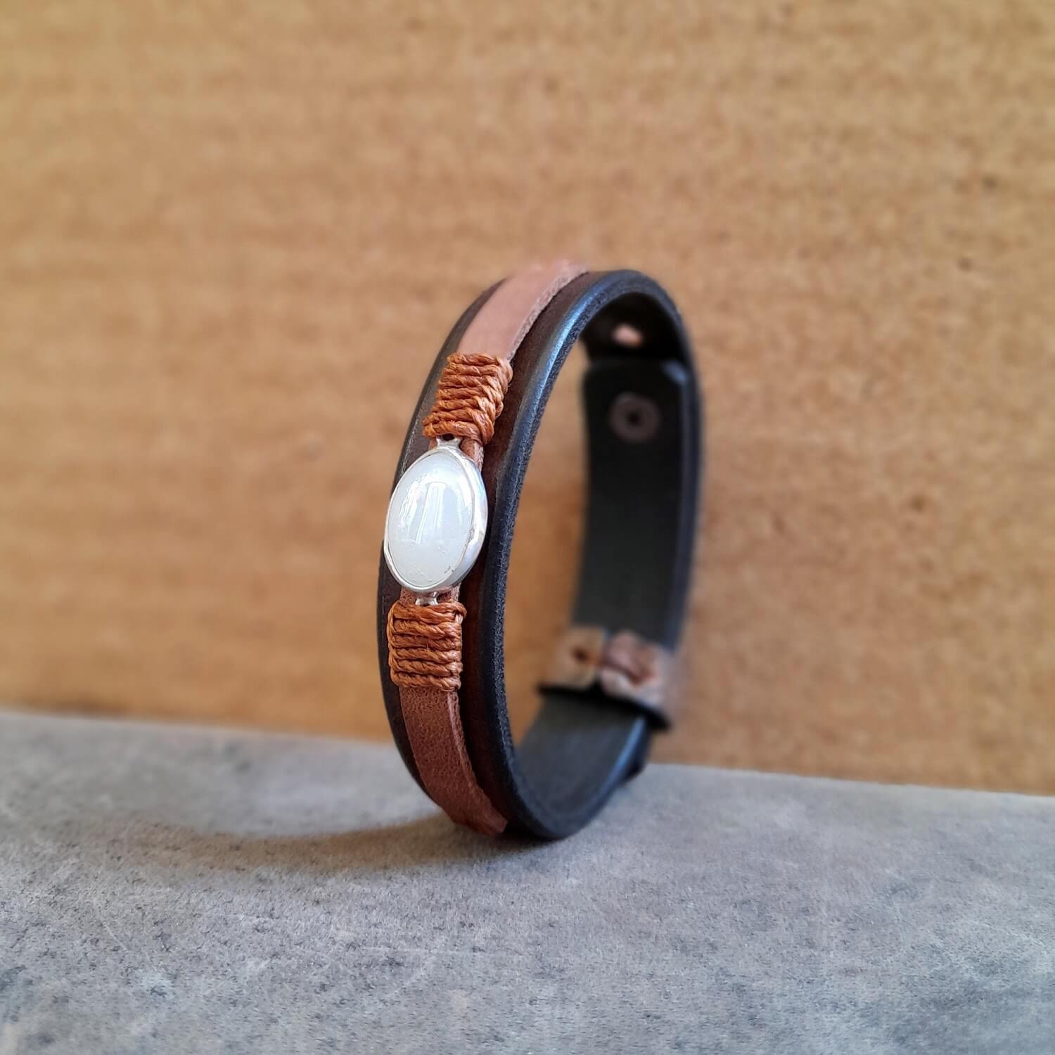 The OOAK Moonstone Glow Bracelet: A layered chestnut brown and earthy soil brown full-grain leather bracelet featuring an oval natural moonstone on a sterling silver pendant, wrapped with warm brown cord.
