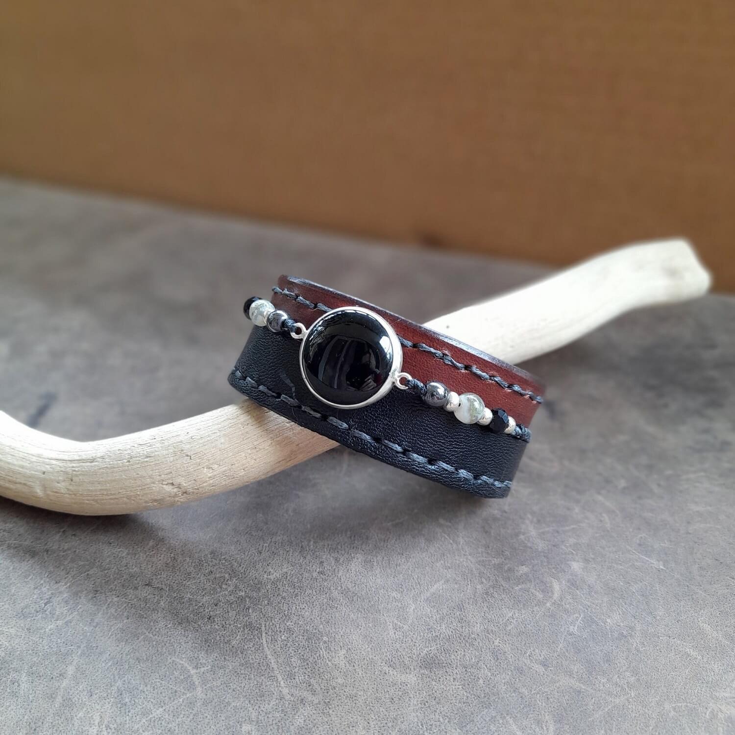 The OOAK Obsidian Power Cuff: A chunky brown Vachetta full-grain leather bracelet with a black asymmetrical top layer, featuring a prominent black obsidian on a polished sterling silver cabochon, and a row of braided hematite, onyx, and smoky quartz beads.