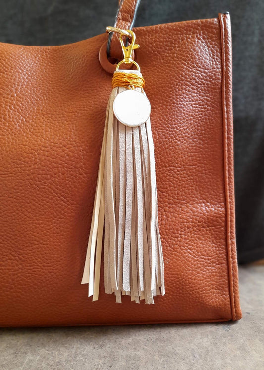 Detailed close-up of the large Howlite disc pendant on the Serene Howlite Charm, highlighting its smooth texture, soft white color, and unique gray veining while attached on a brown leather bag