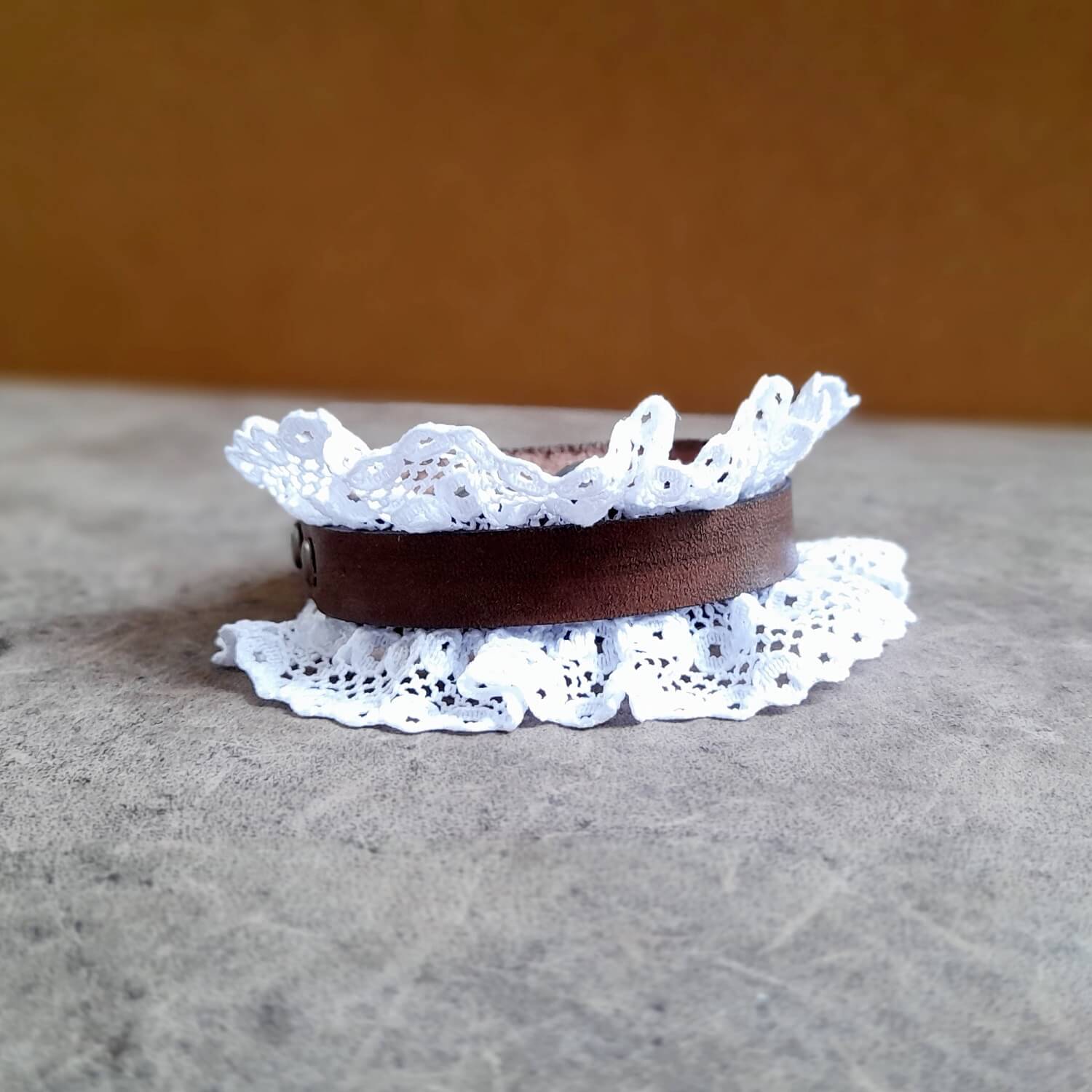 Close-up of the delicate lace and antique bronze stud rivets on The Prairie Lace Cuff, highlighting the intricate texture and contrast with the leather.