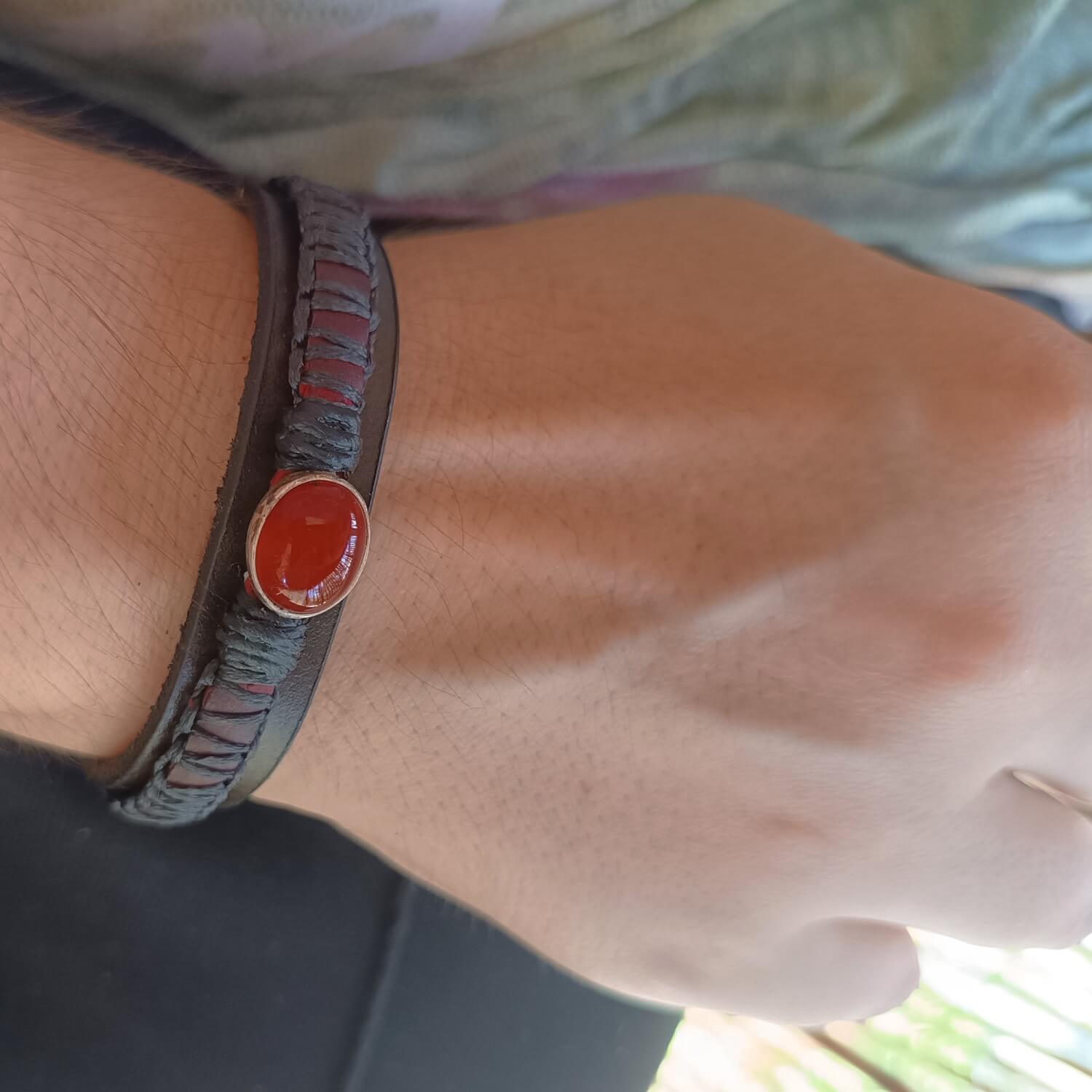 The Roamer Leather Bracelet worn on a woman's wrist, showcasing its layered design, dark leather tones, and the subtle pop of the red Carnelian gemstone, fitting comfortably while adding savage style to a woman too.