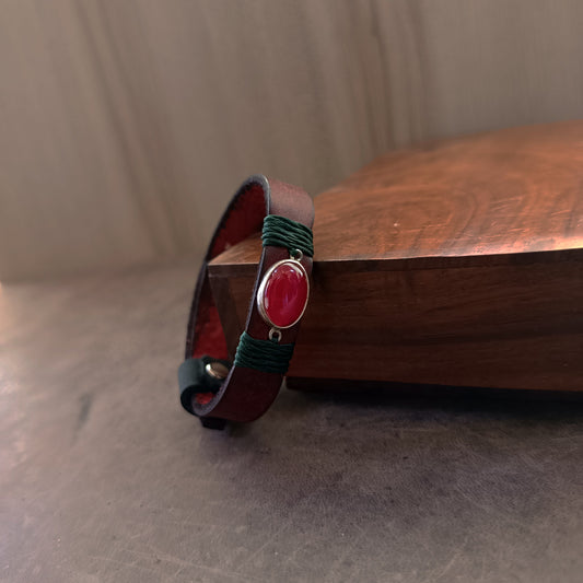 Close up Side view of the dark red Crazy Horse leather texture and the deep forest green waxed cord wrap on The Rooted Glow Bracelet, showing the quality and contrast of materials.