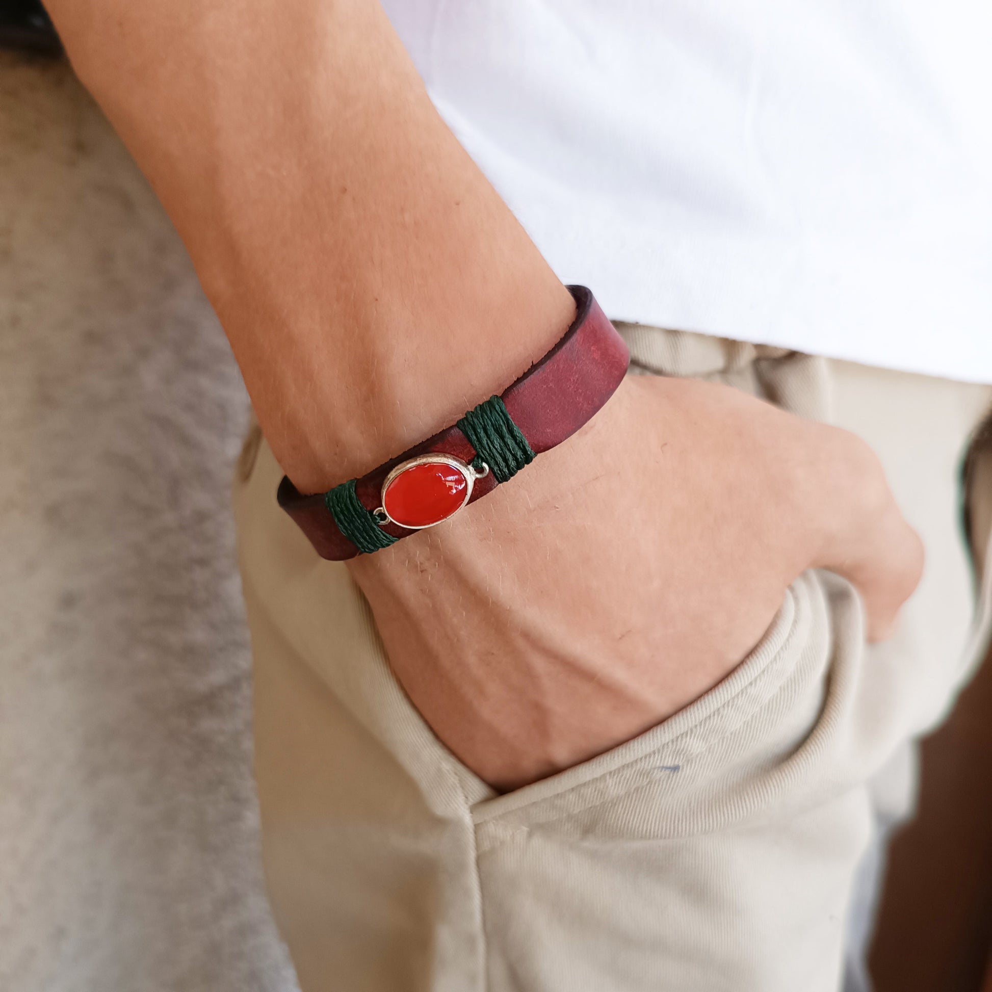 The Rooted Glow Cherry Agate Bracelet worn on a wrist, showcasing its minimalist wrap style, comfortable fit, and the distinct red leather and green cord.
