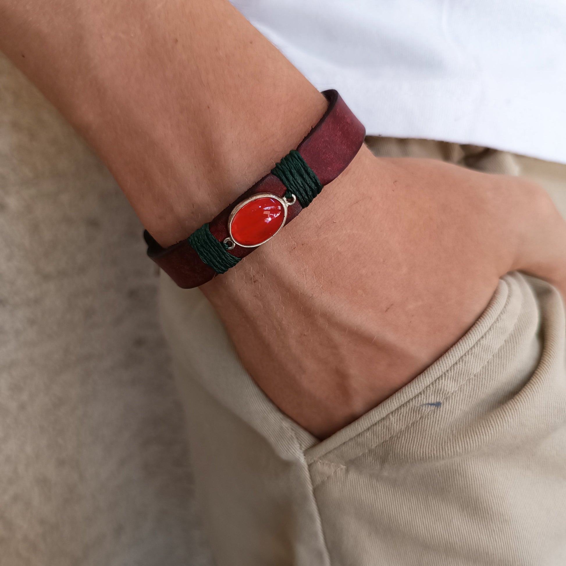 The Rooted Glow Cherry Agate Bracelet worn on a wrist close up, showcasing its minimalist wrap style, comfortable fit, and the distinct red leather and green cord.
