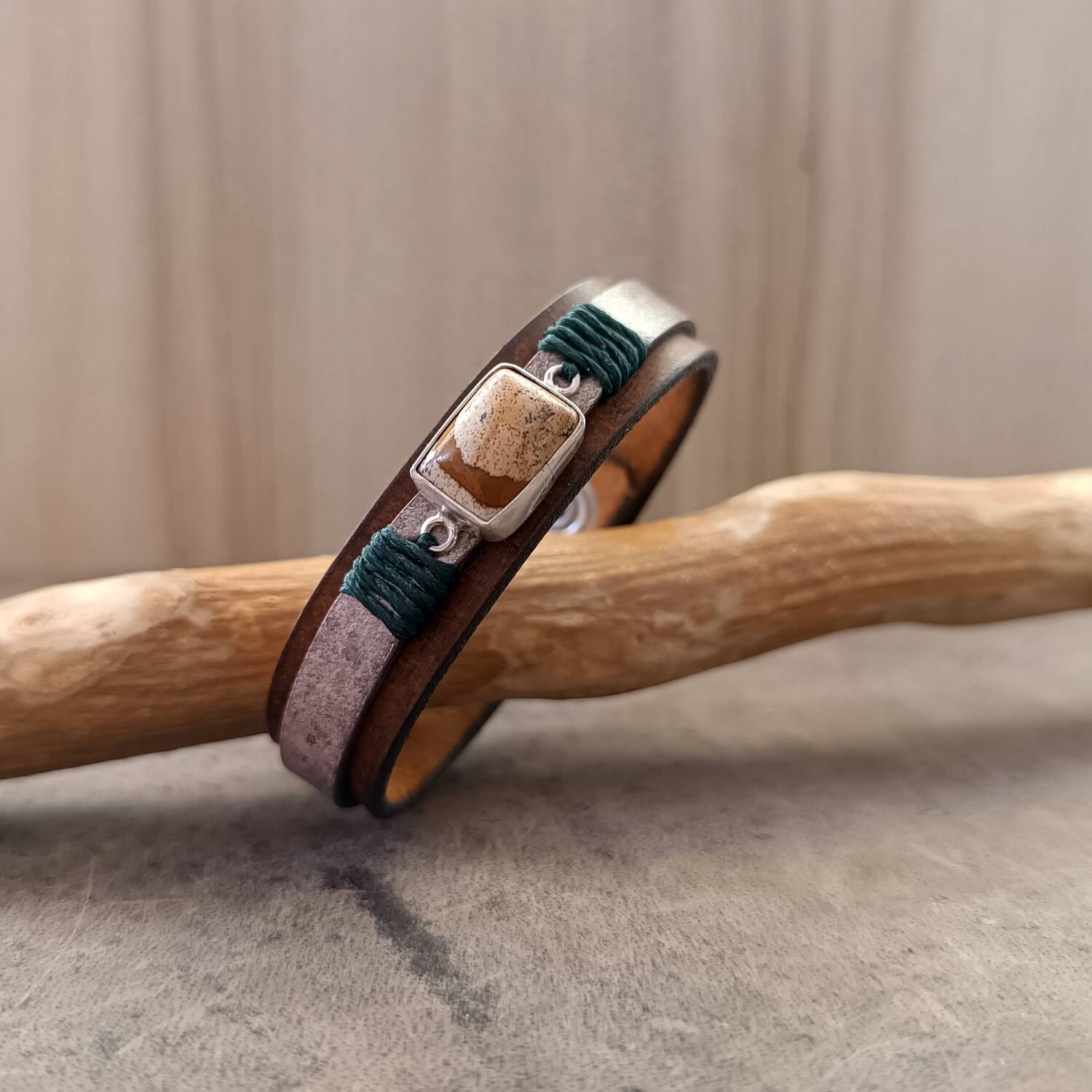 Close-up of the layered dark brown and marbled beige vachetta leather, showing the blackened edges, polished finish, and the subtle forest green waxed cord on The Silent Witness Bracelet.
