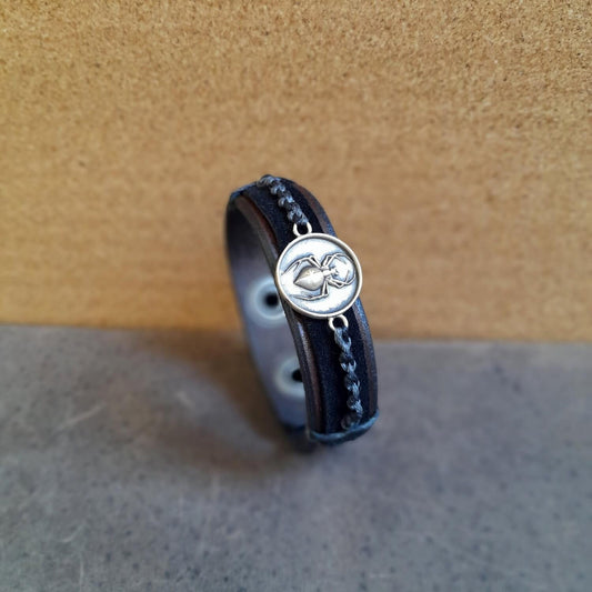 The Spider Ally Bracelet: A layered chestnut brown and matte black leather bracelet with a black and dark gray macramé cord, featuring a hand-crafted oxidized brass spider pendant.