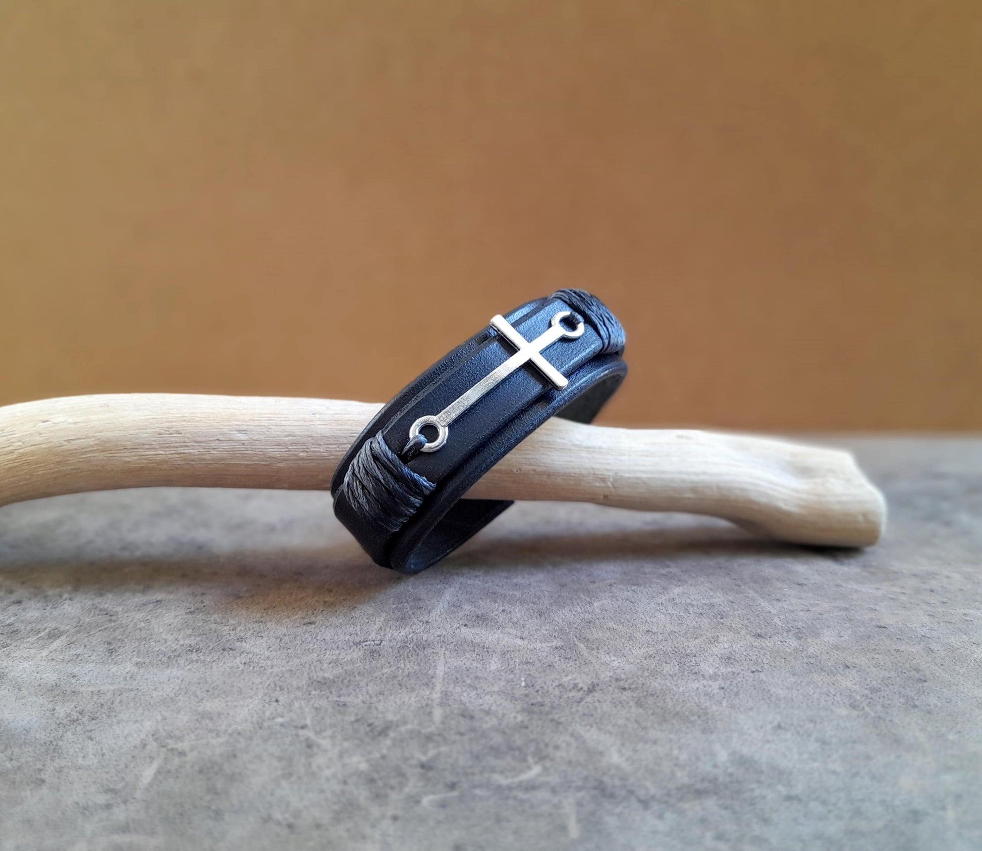 The Steadfast Spirit Cross Bracelet, all-black version, side view. Features a large horizontal stainless steel silver cross on a dual-layered black full-grain leather band.